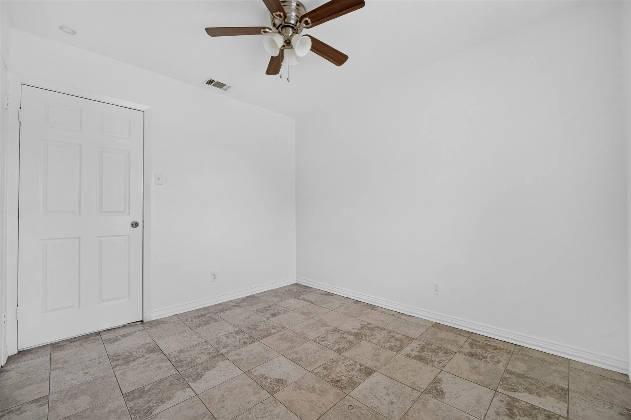 Spacious room featuring tile flooring throughout and a ceiling fan with brushed metal finish