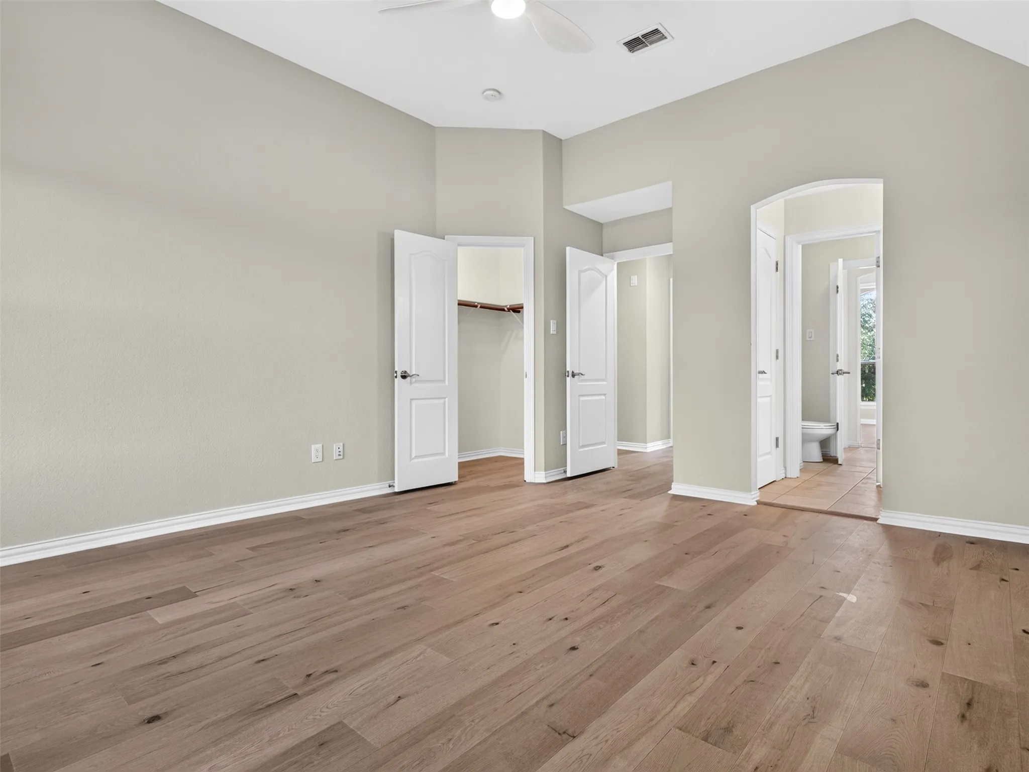 Vaulted ceilings, wood-finish flooring, white panel doors, and neutral wall tones