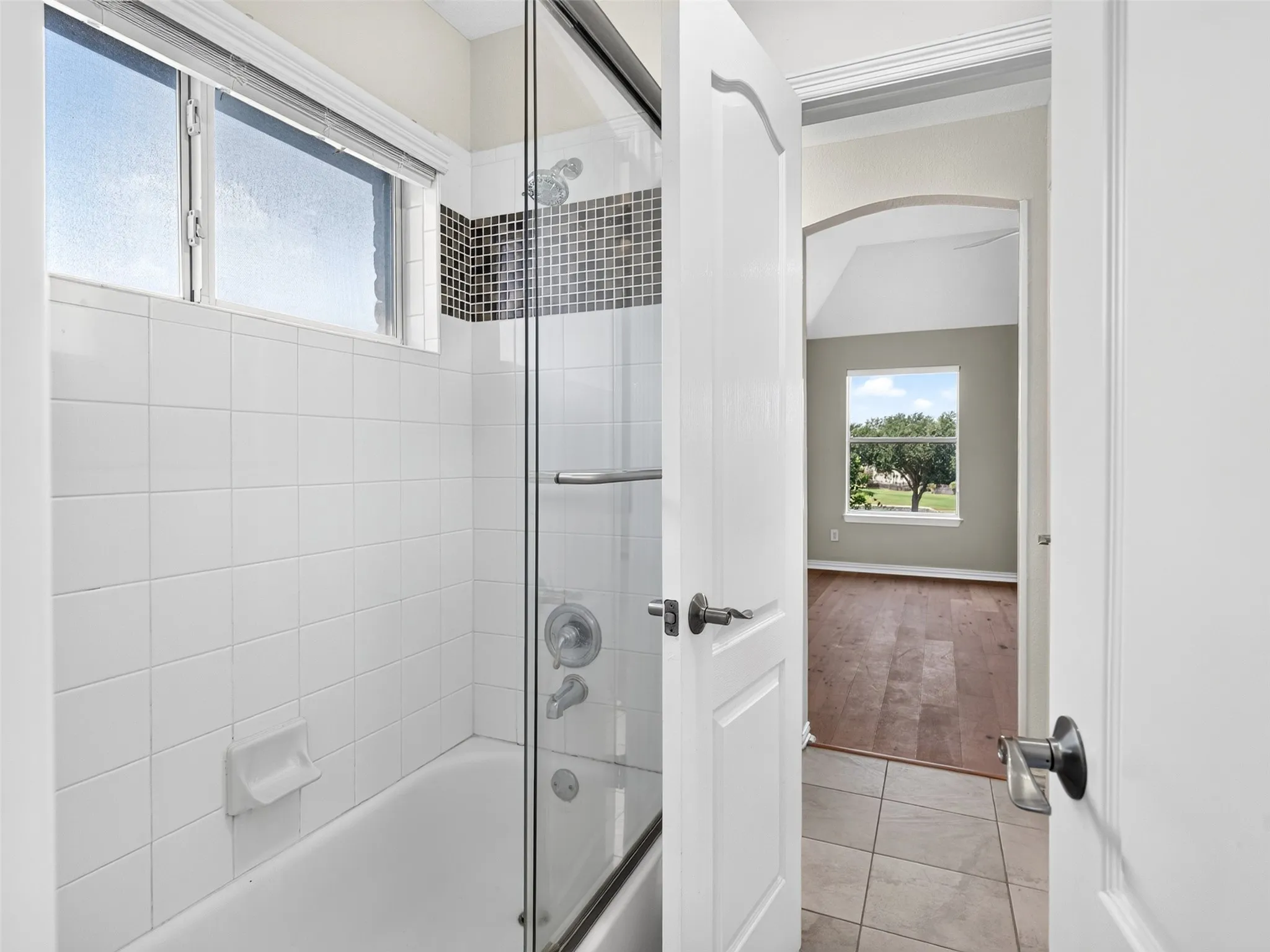 Tub/shower combination featuring a mosaic tile accent and glass enclosure