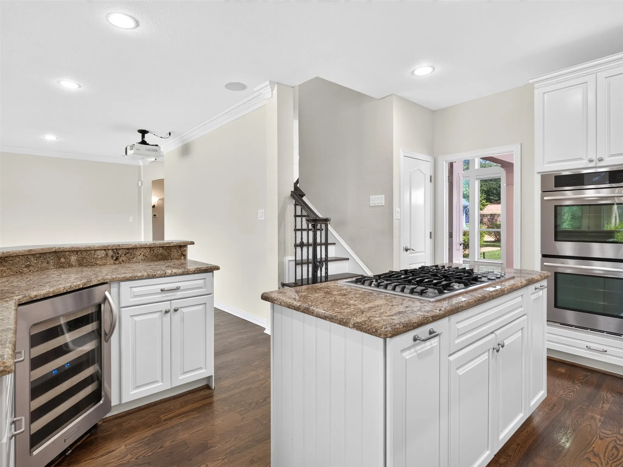 Gourmet kitchen featuring a built-in wine refrigerator, white cabinetry, a gas cooktop, double wall ovens, and wood-finish flooring