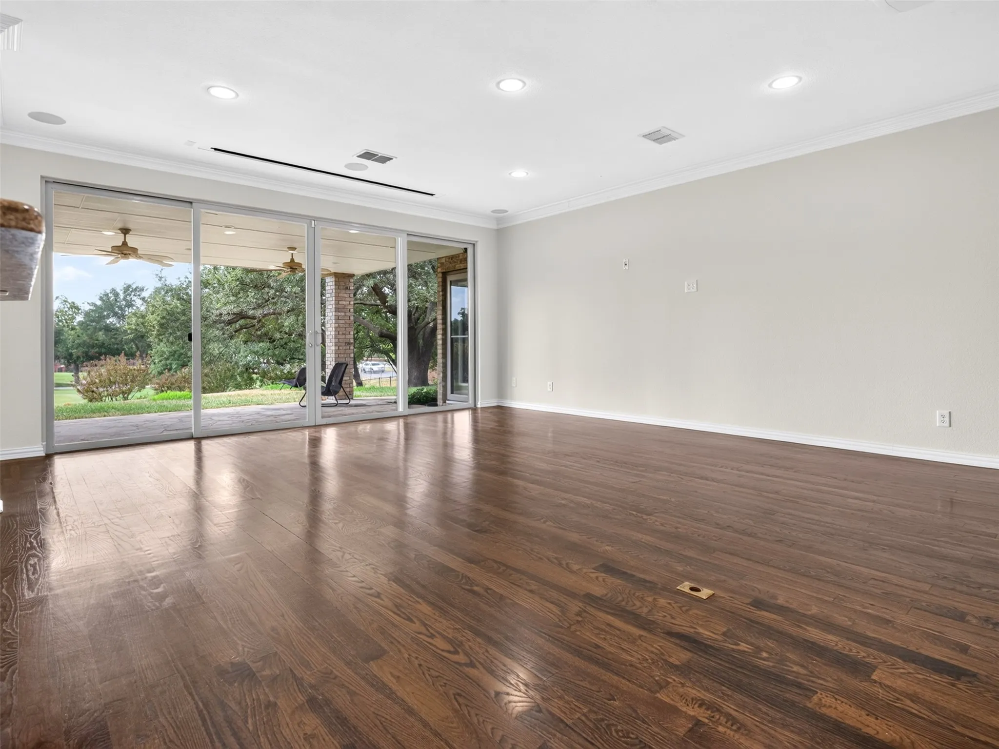 Hardwood flooring, recessed lighting, crown molding, and a sliding glass door opening to a covered patio