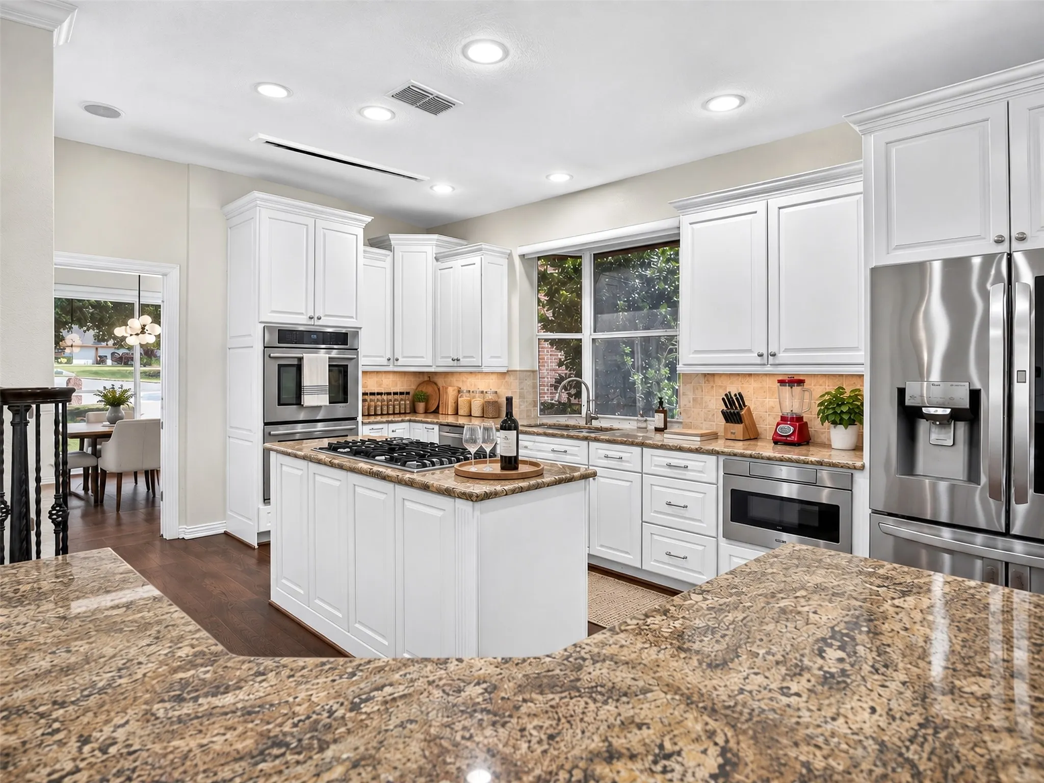 Kitchen featuring granite countertops, white cabinetry, stainless steel appliances, a center island with a gas cooktop, and recessed lighting