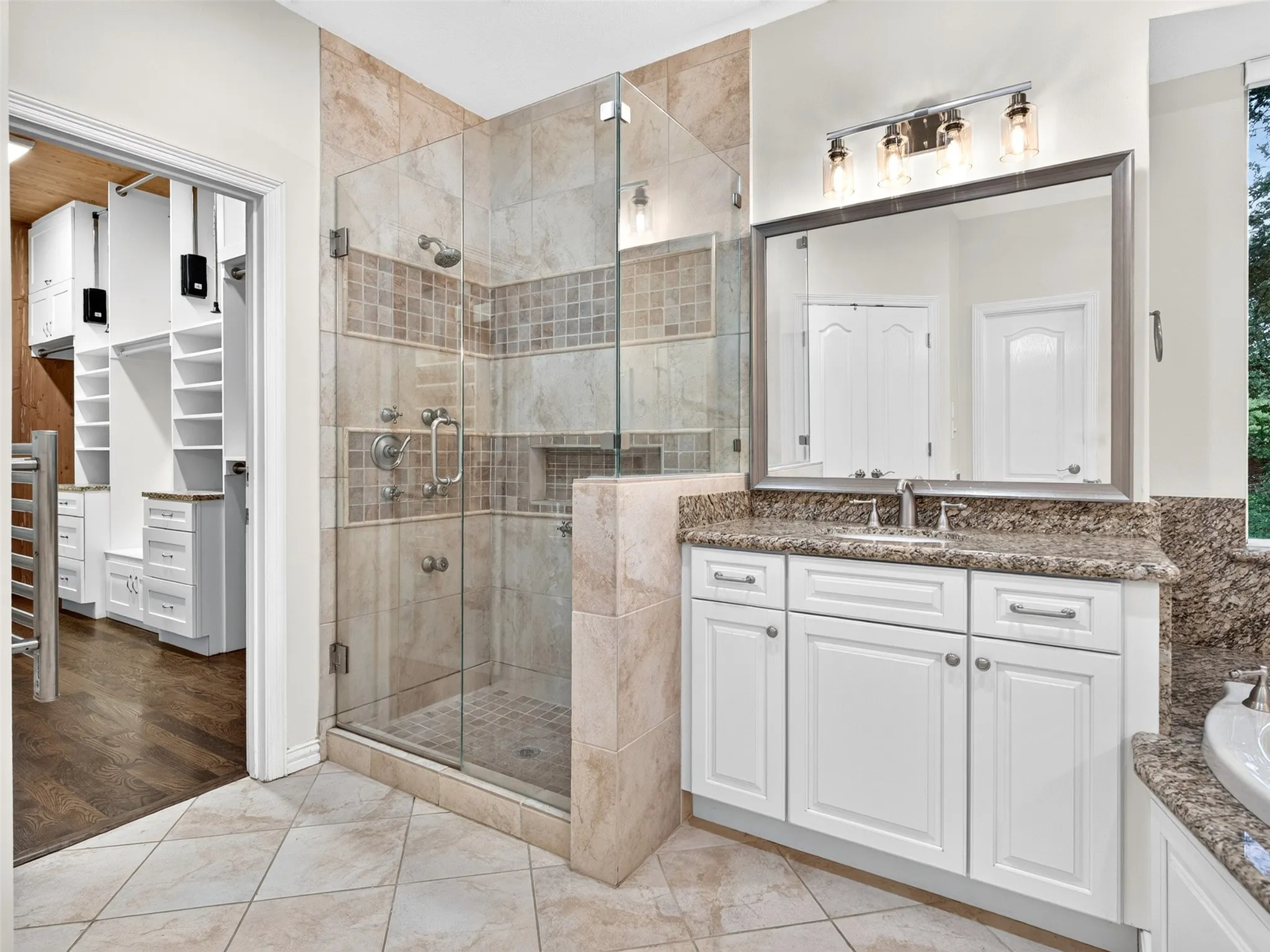 Walk-in shower with glass enclosure, single vanity with white cabinetry, polished chrome fixtures, and tile flooring