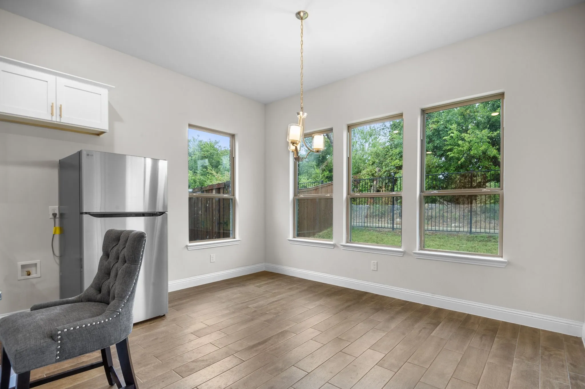 Kitchen with hardwood / wood-style floors, stainless steel fridge, pendant lighting, and white cabinets