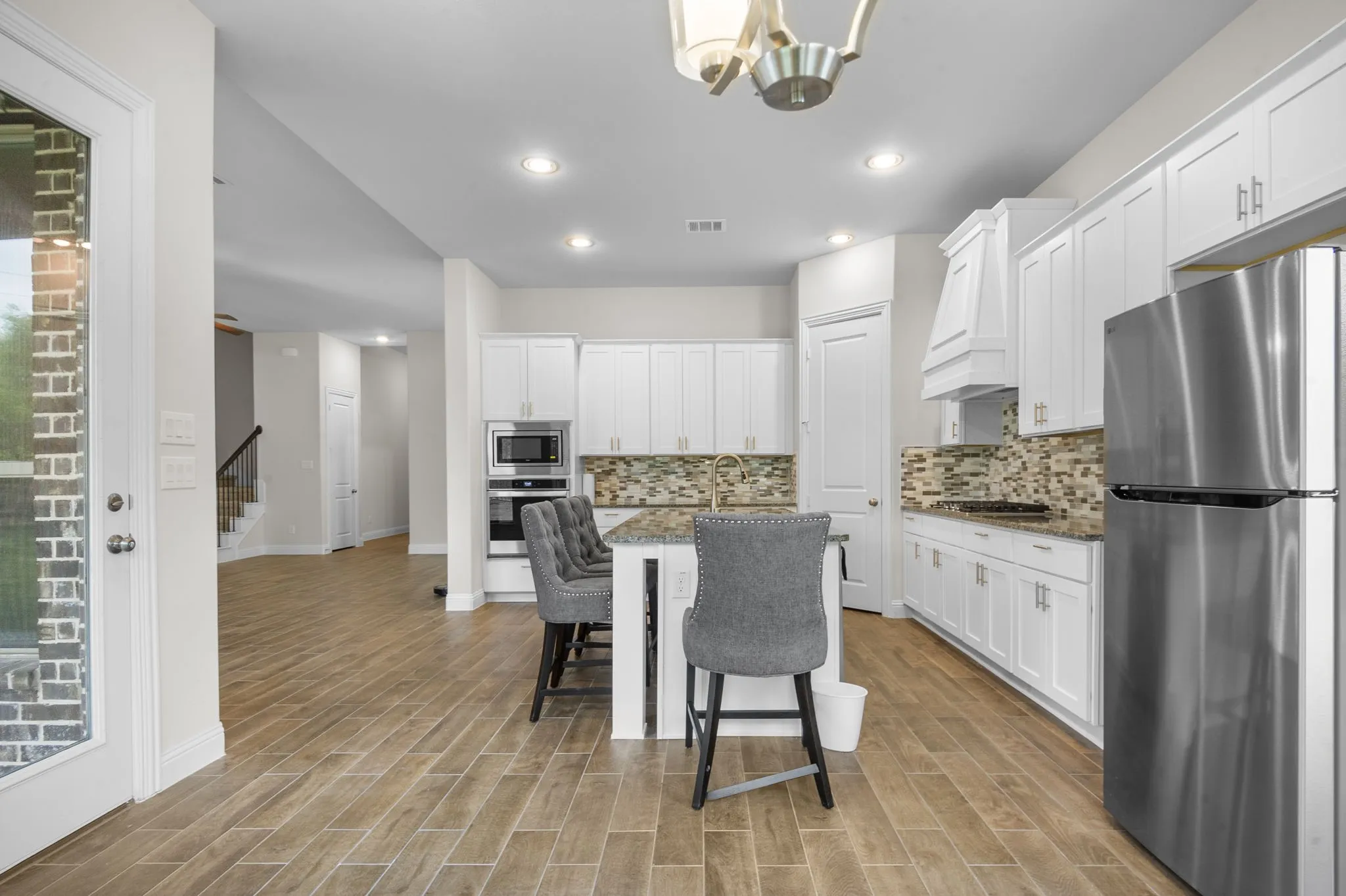 Kitchen with stone counters, appliances with stainless steel finishes, and white cabinetry