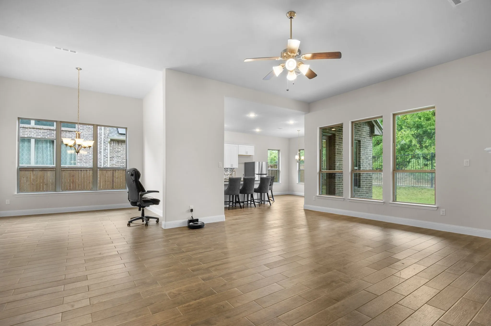 Great room featuring ceiling fan with notable chandelier and light hardwood / wood-style flooring