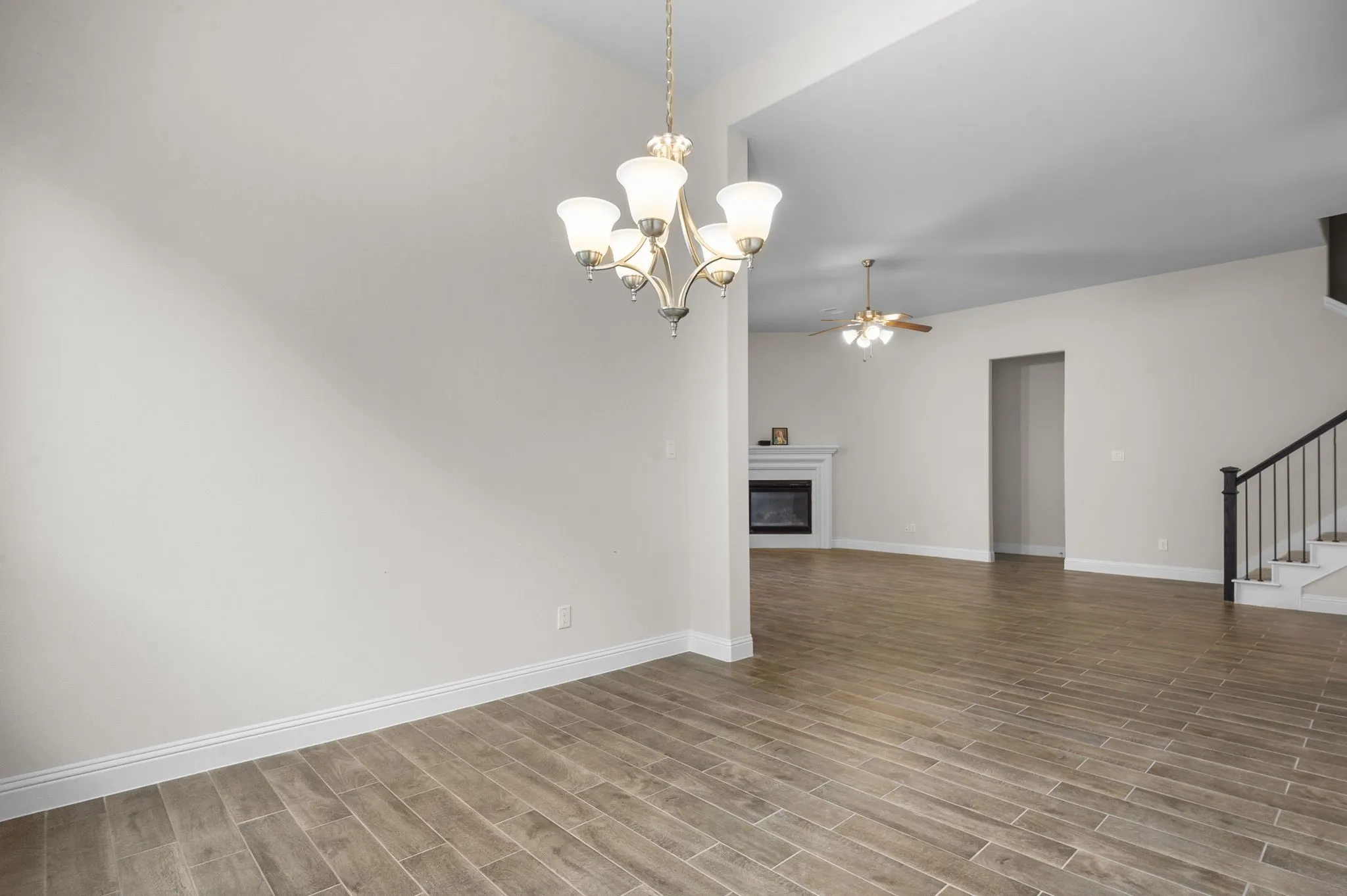 Unfurnished living room featuring light wood-type flooring and ceiling fan with notable chandelier