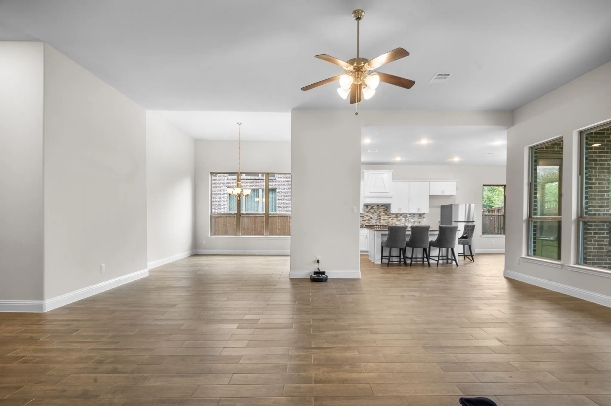 Unfurnished living room with ceiling fan with notable chandelier and wood-type flooring