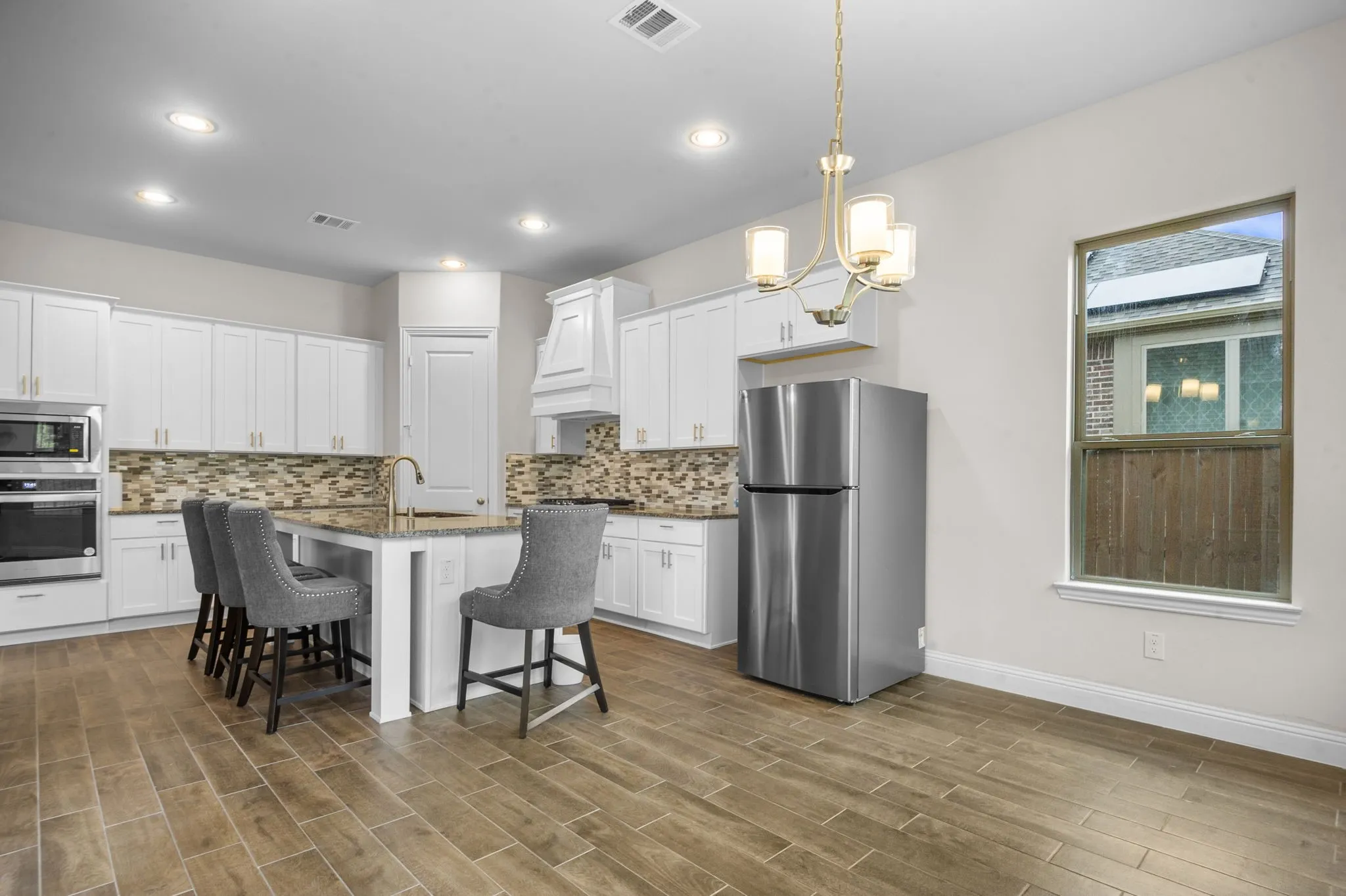 Kitchen with an island with sink, a breakfast bar, appliances with stainless steel finishes, and white cabinets