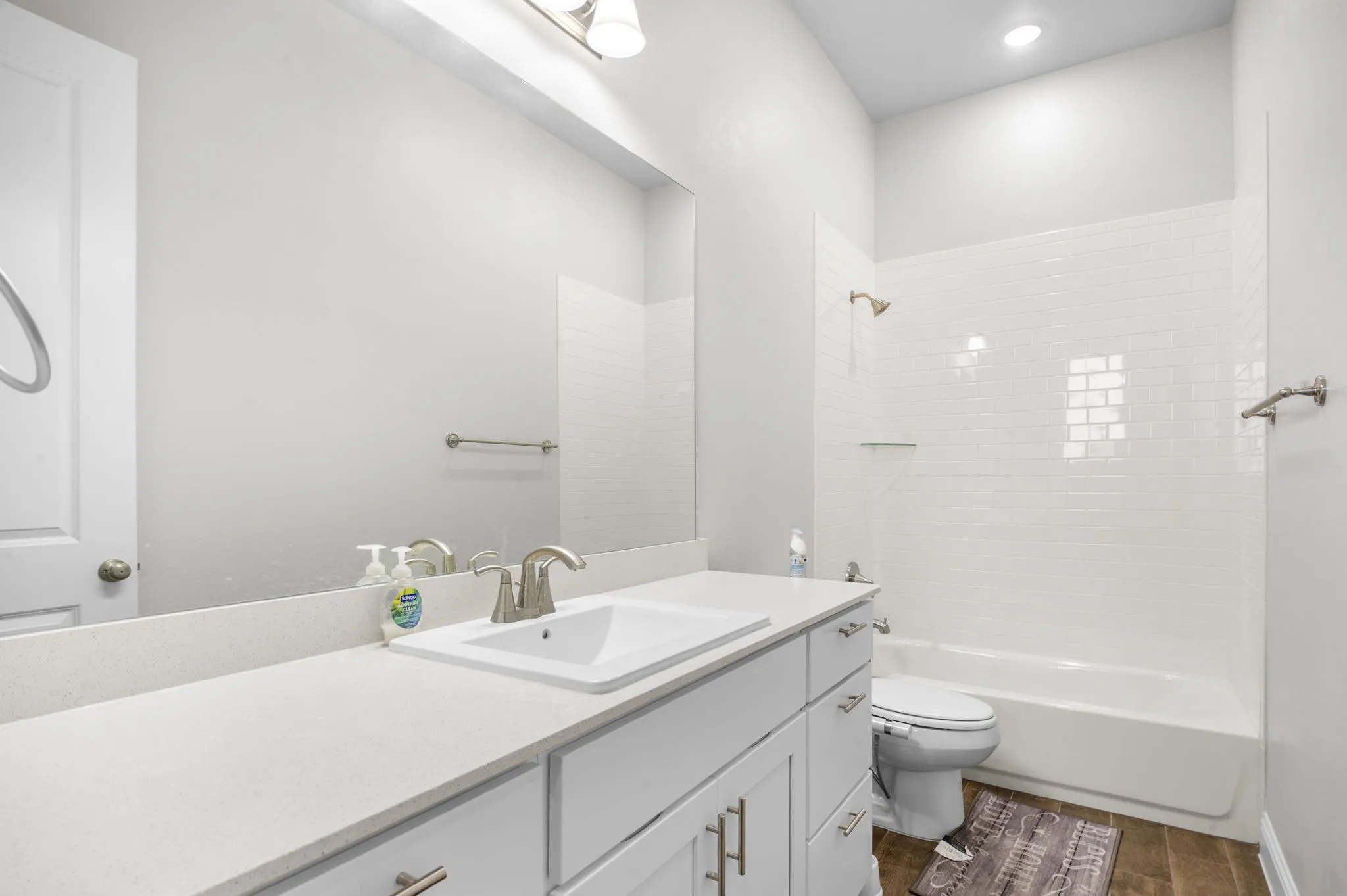 Full bathroom featuring vanity, toilet, washtub / shower combination, and hardwood / wood-style floors