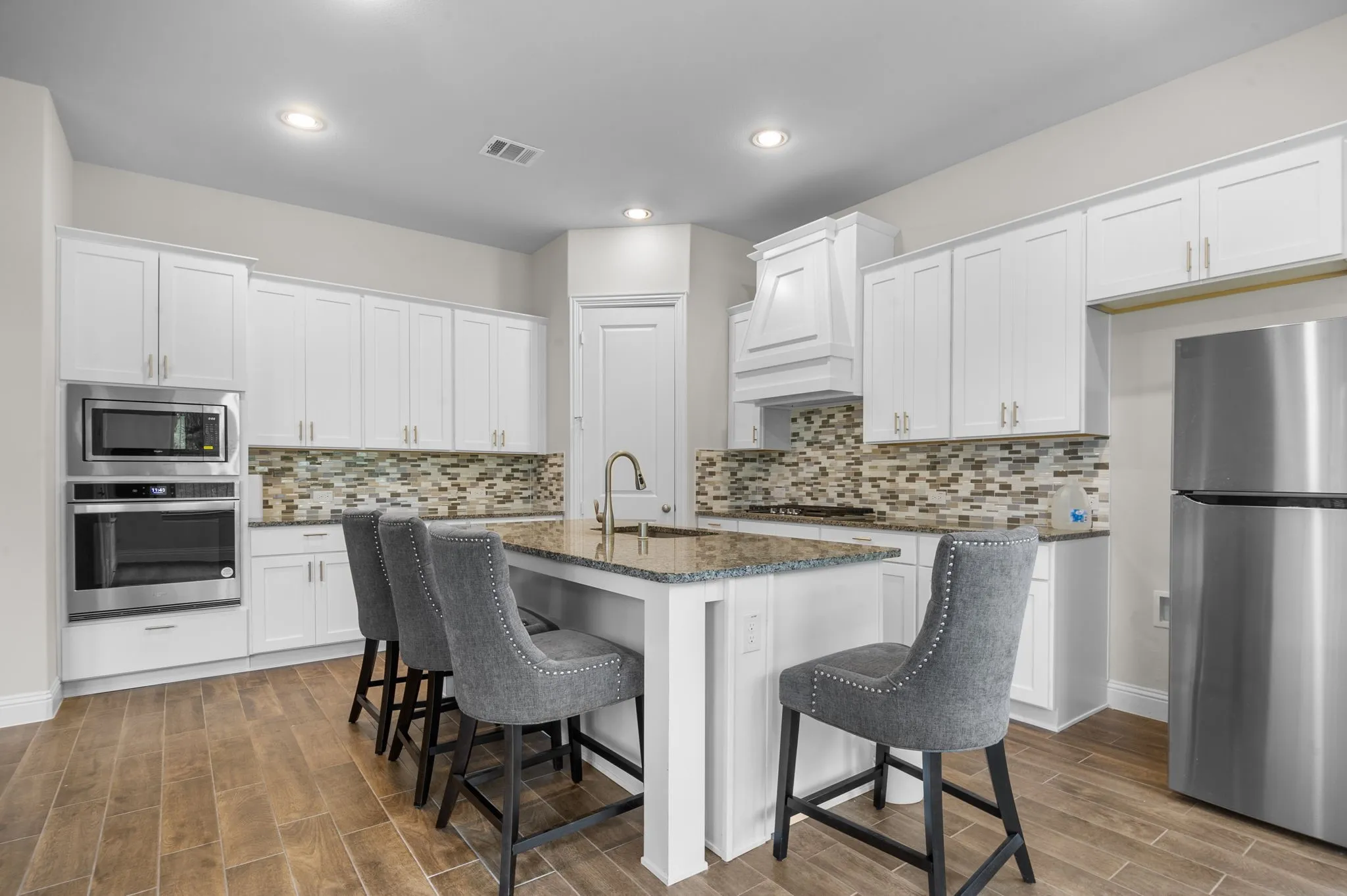 Kitchen with stainless steel appliances, sink, white cabinetry, and a kitchen island with sink