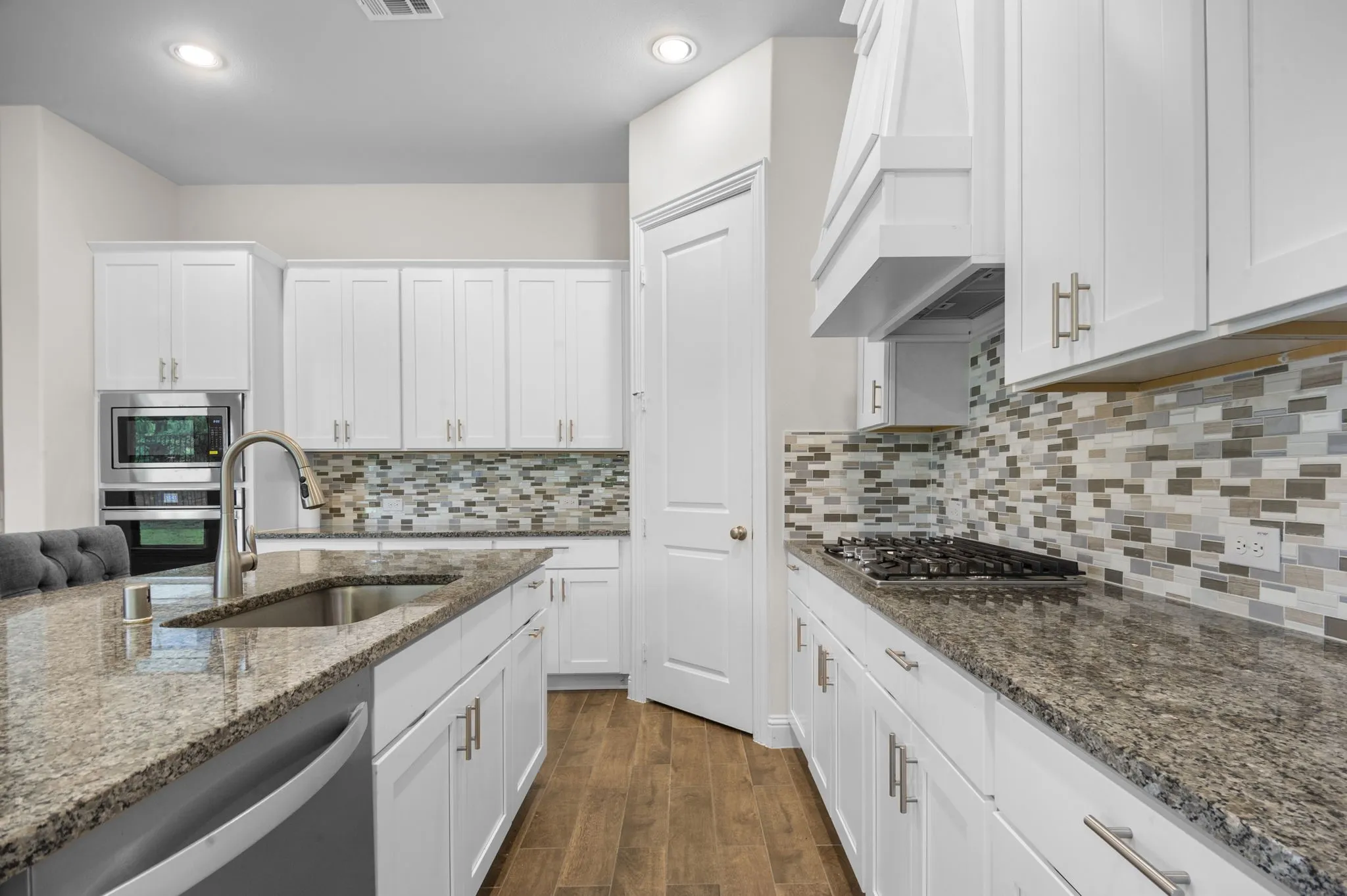 Kitchen with dark hardwood / wood-style flooring, stone countertops, stainless steel appliances, sink, and custom exhaust hood