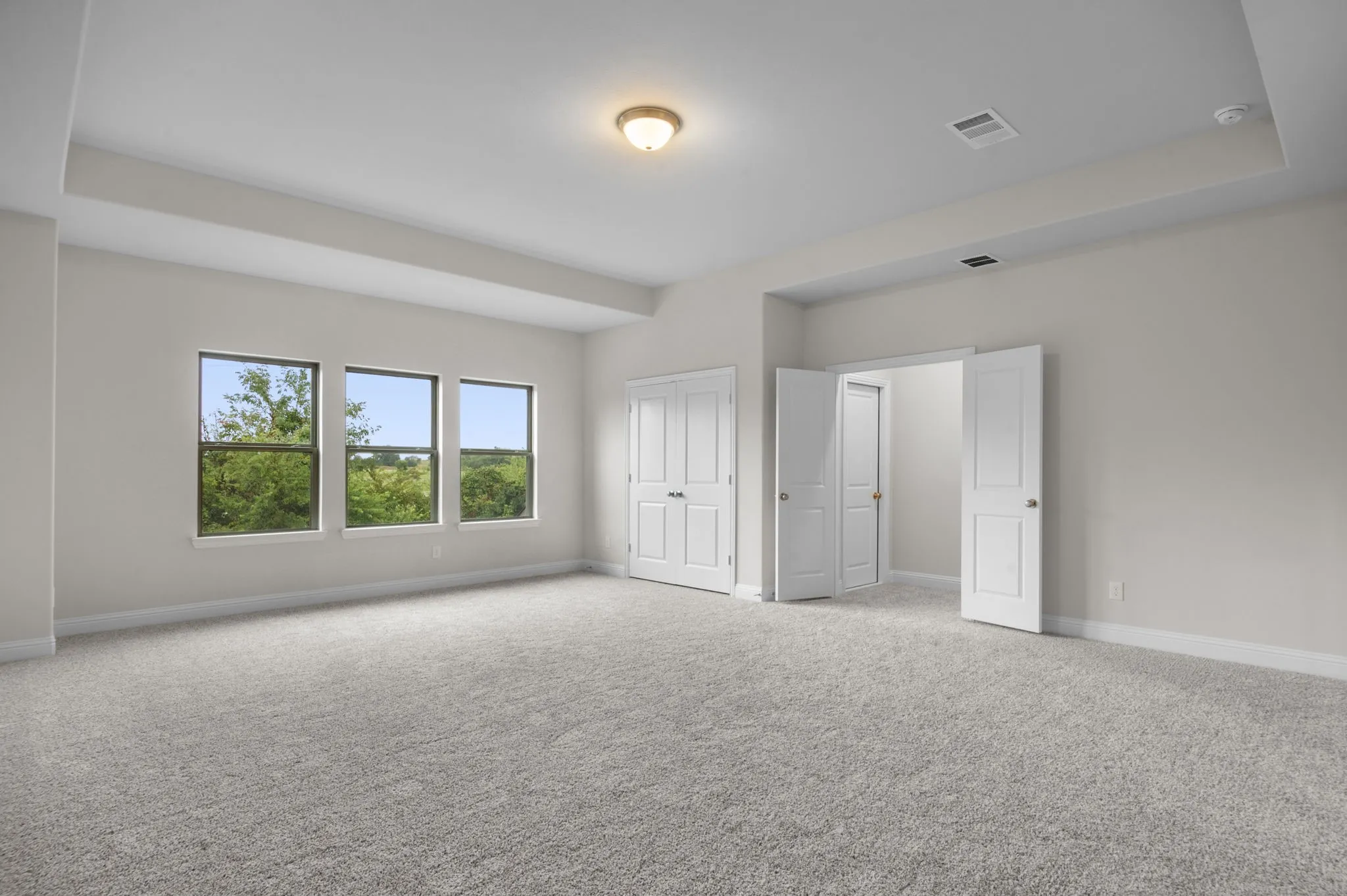 Unfurnished bedroom with light colored carpet and a raised ceiling