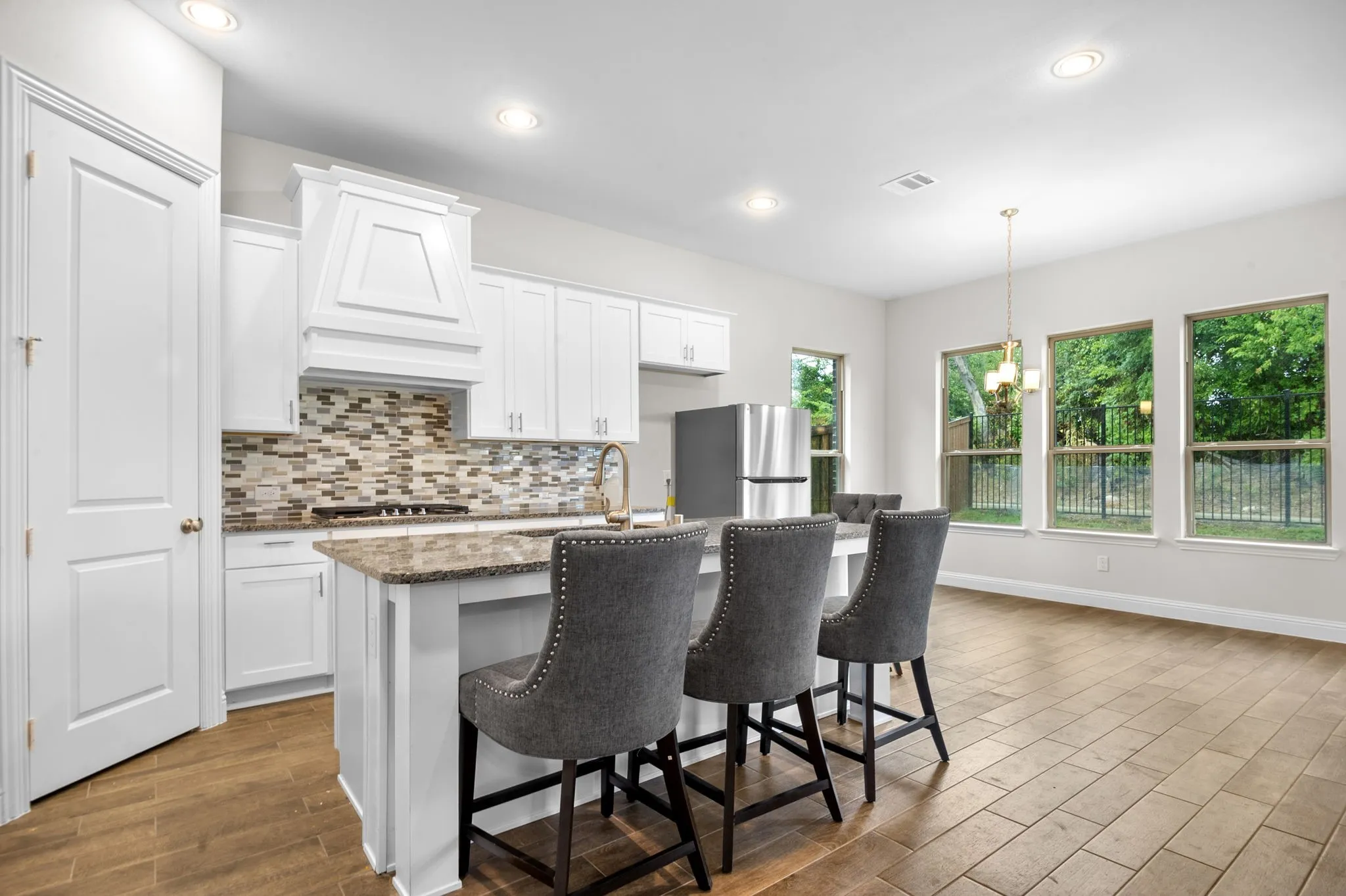 Kitchen featuring a center island with sink, light hardwood / wood-style flooring, premium range hood, stainless steel appliances, and white cabinetry