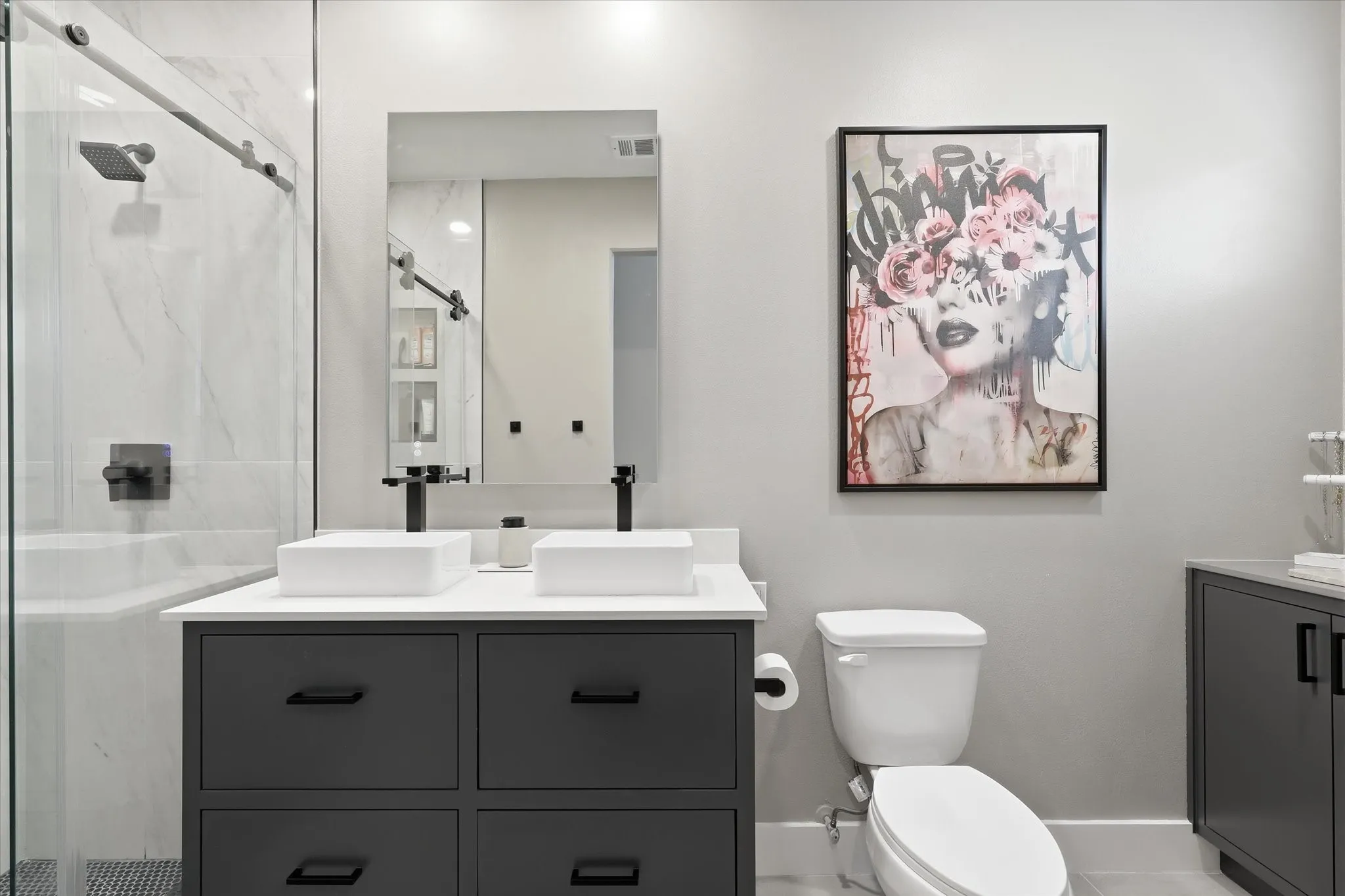 Modern primary bathroom featuring a floating vanity with dual rectangular vessel sinks, matte black hardware and fittings, and a quartz countertop