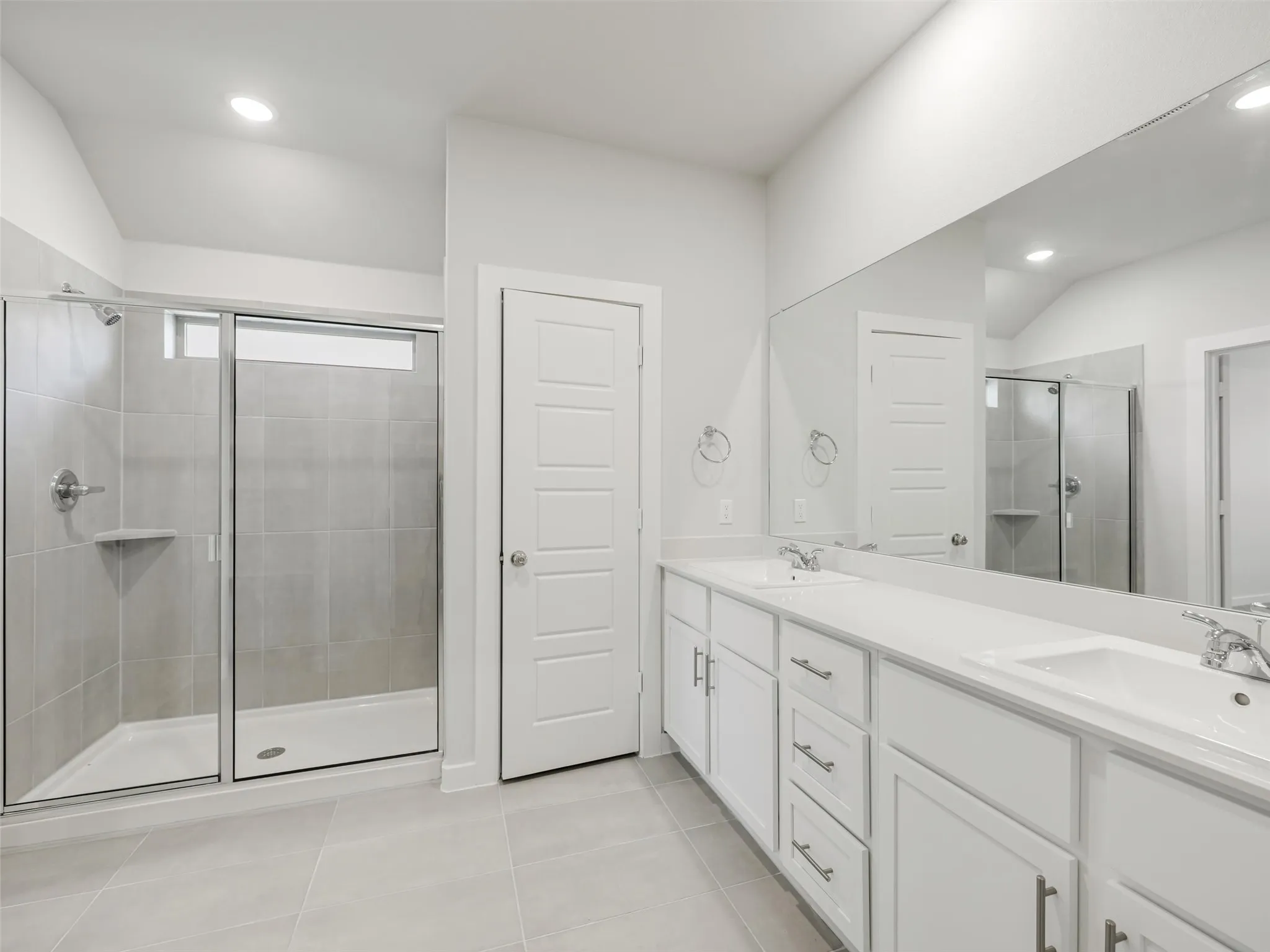 Primary Bathroom featuring dual vanities with white cabinetry, white quartz countertops, and chrome fixtures