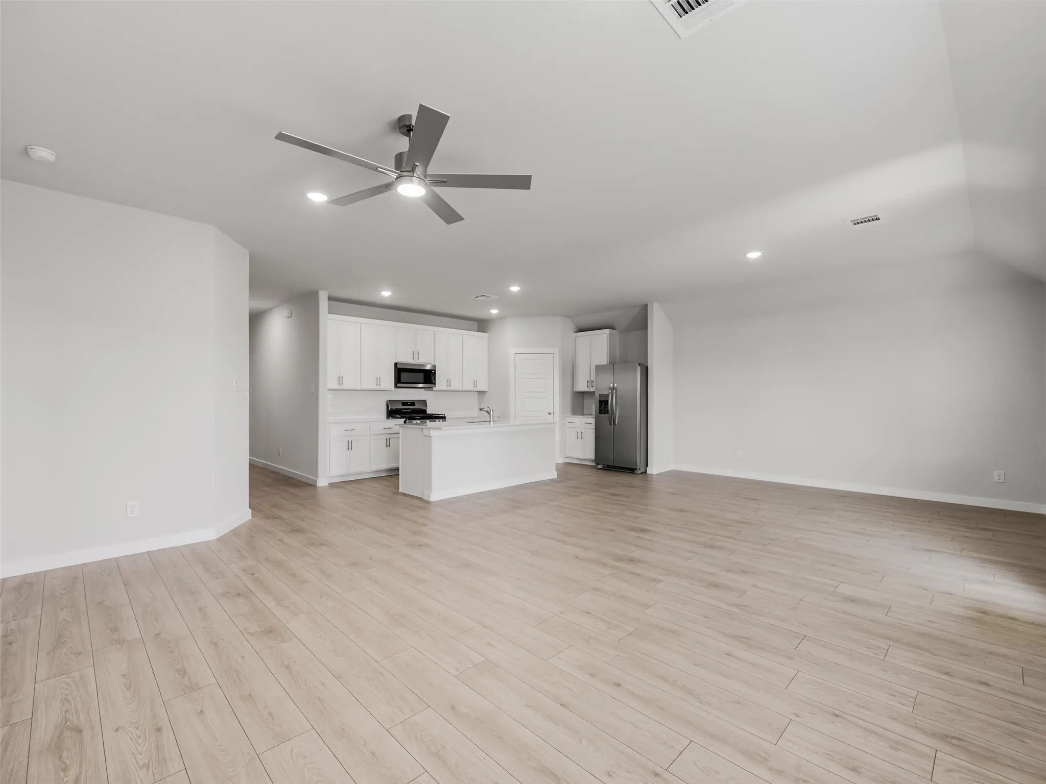 Open-concept living space featuring engineered wood-finish flooring throughout, recessed lighting, and a modern ceiling fan with integrated light fixture
