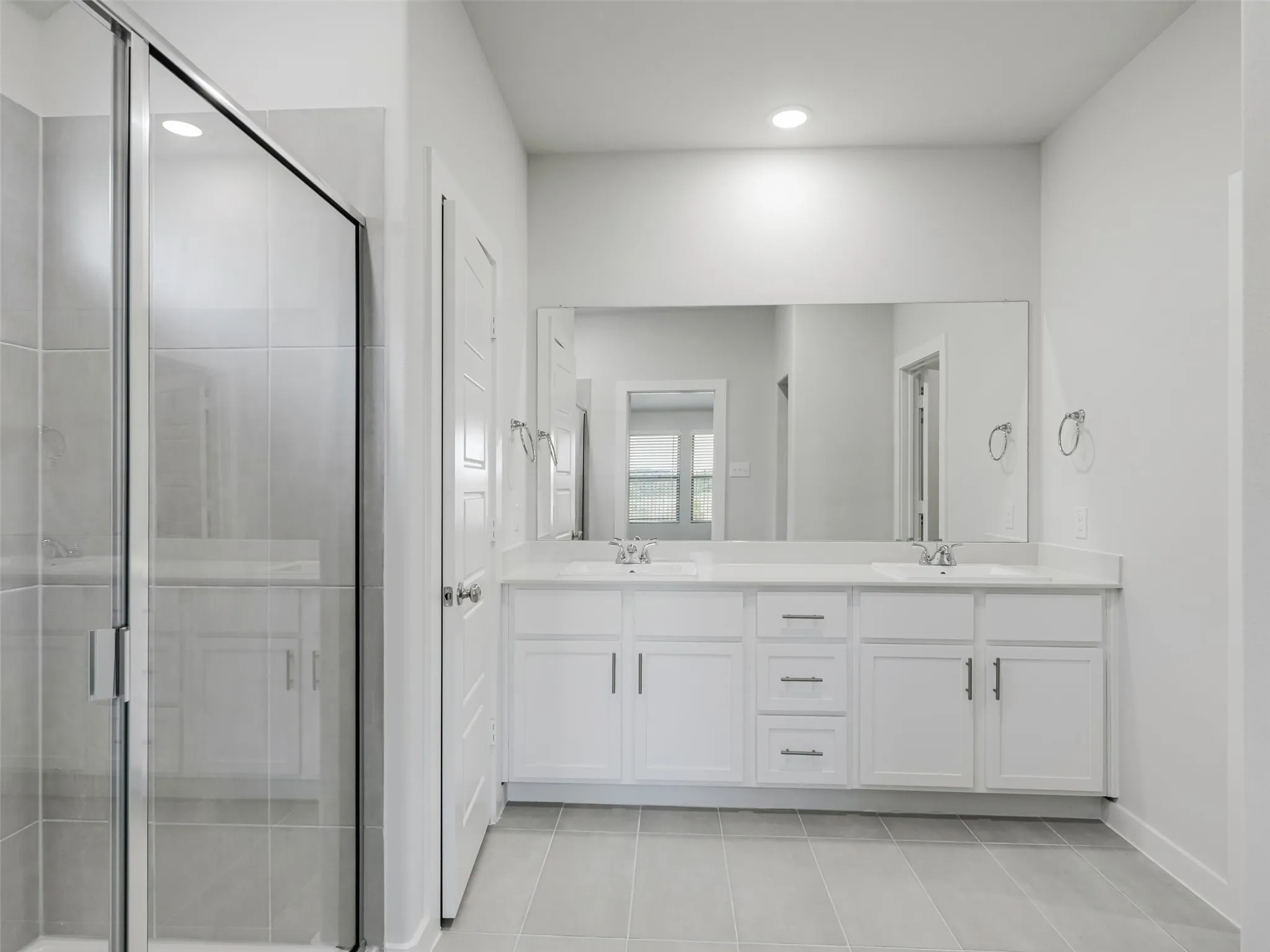 Spa-inspired primary bathroom featuring a dual-sink vanity with white cabinetry, brushed nickel hardware, and a quartz countertop
