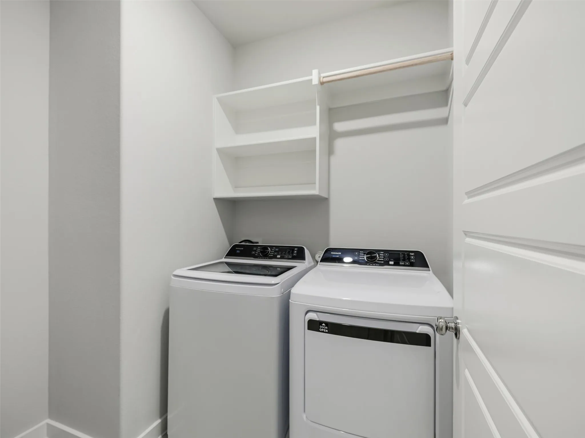 Dedicated laundry area featuring built-in shelving, a hanging rod, and a modern paneled door