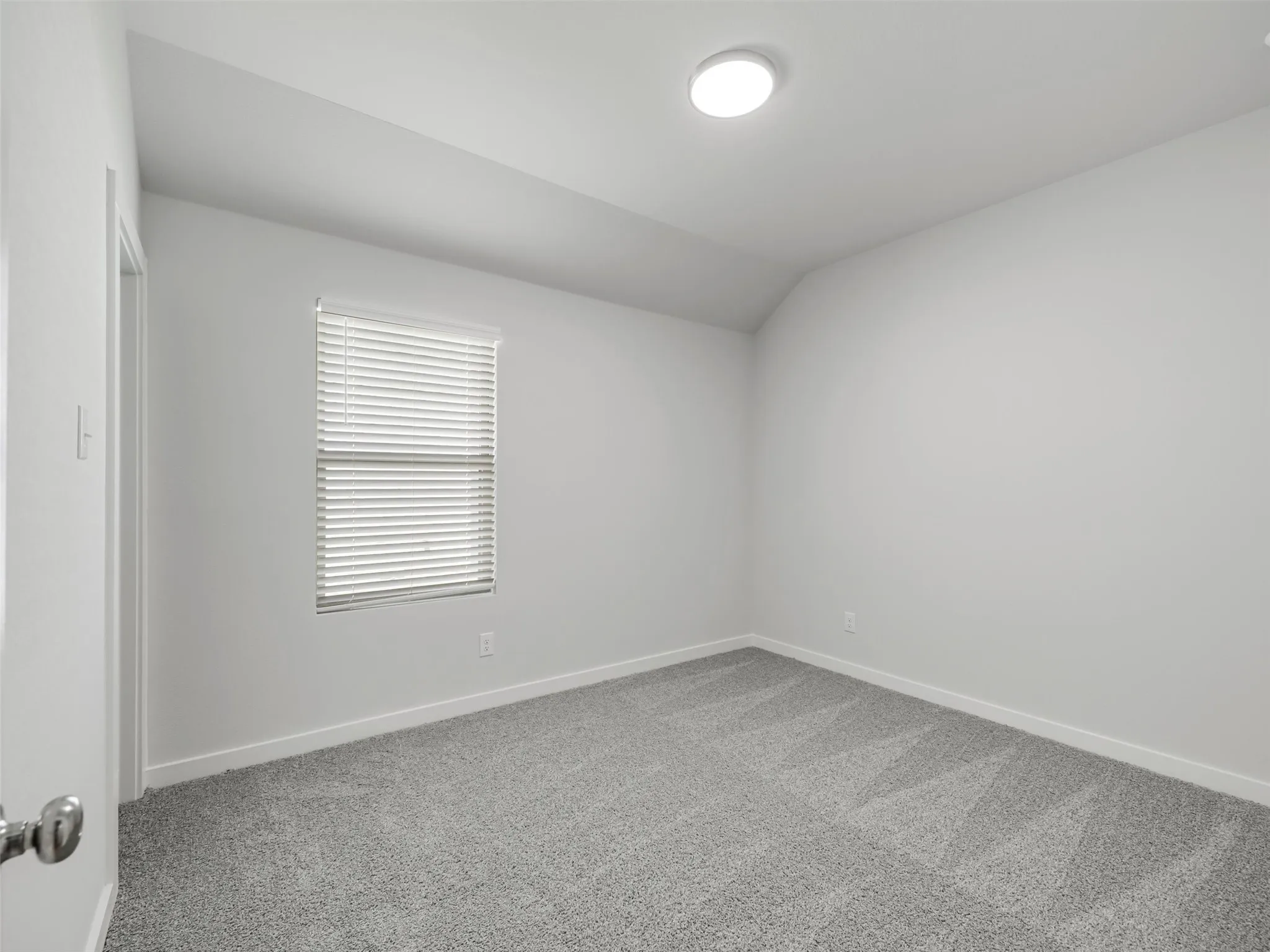 Room featuring light gray carpet, white walls, and a window with horizontal blinds