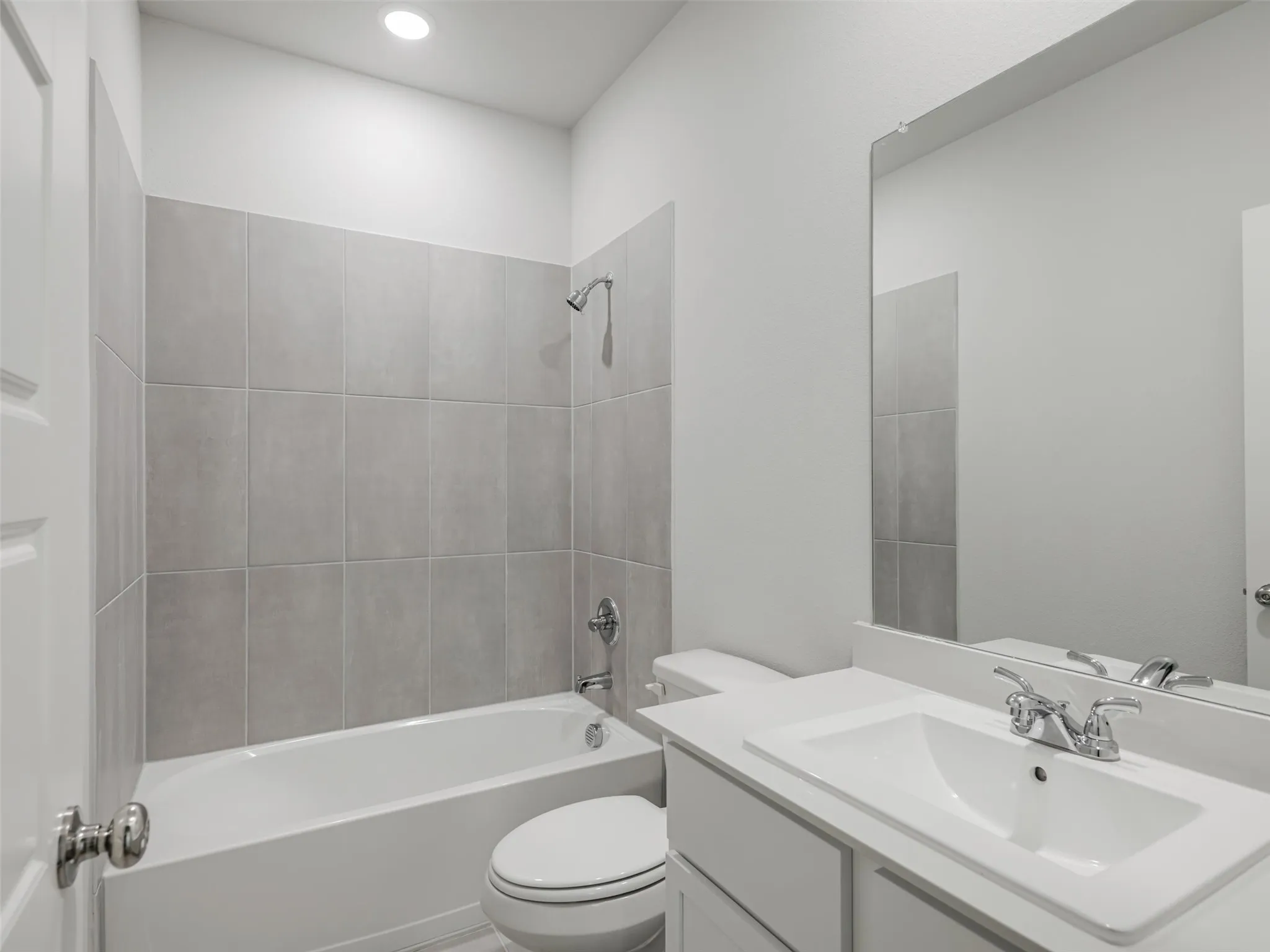 Bathroom featuring a white vanity with integrated sink, chrome faucet, and a large wall-mounted mirror