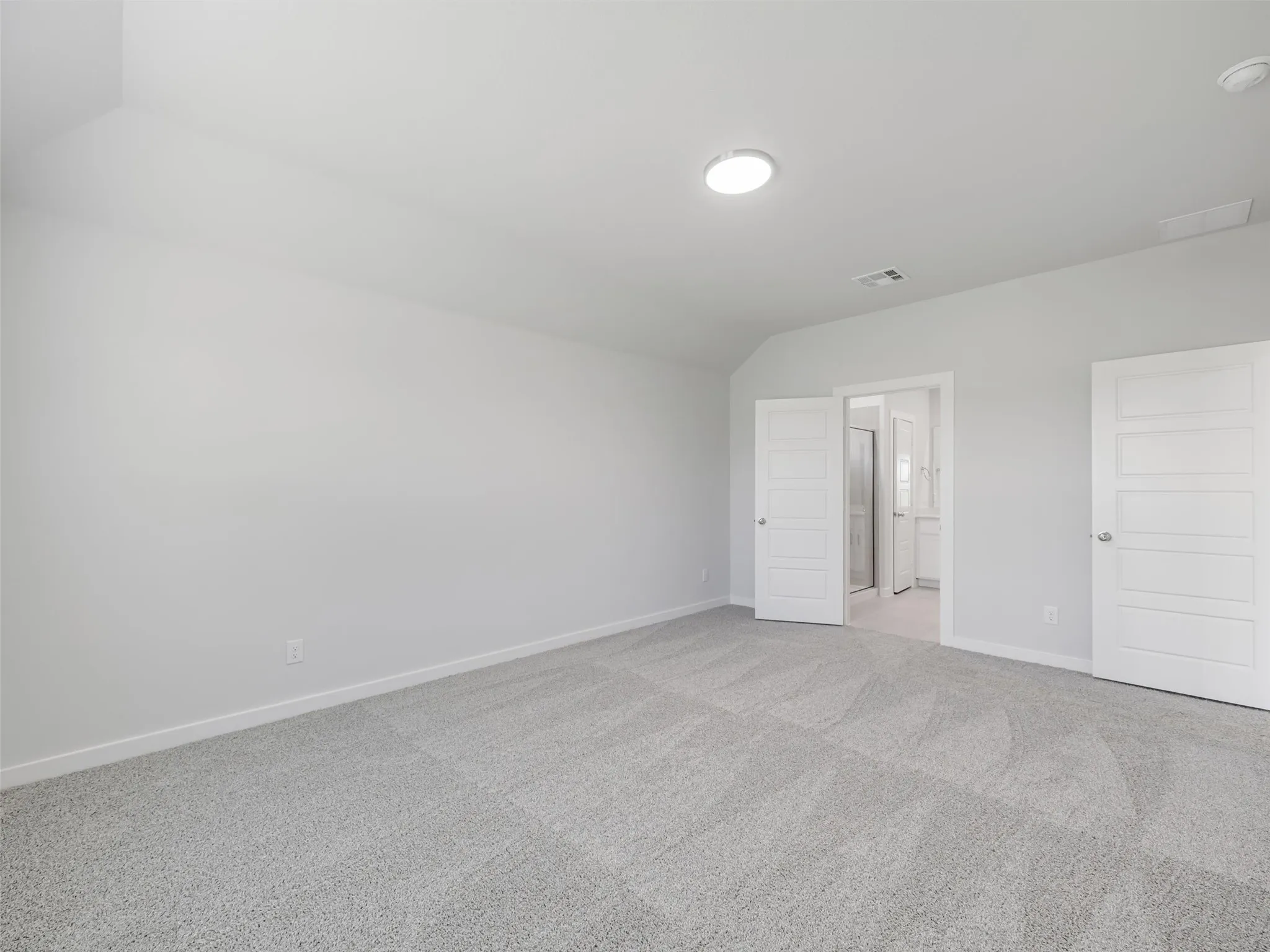 Spacious room featuring light gray carpeting, white walls, and a contemporary flush-mount ceiling light