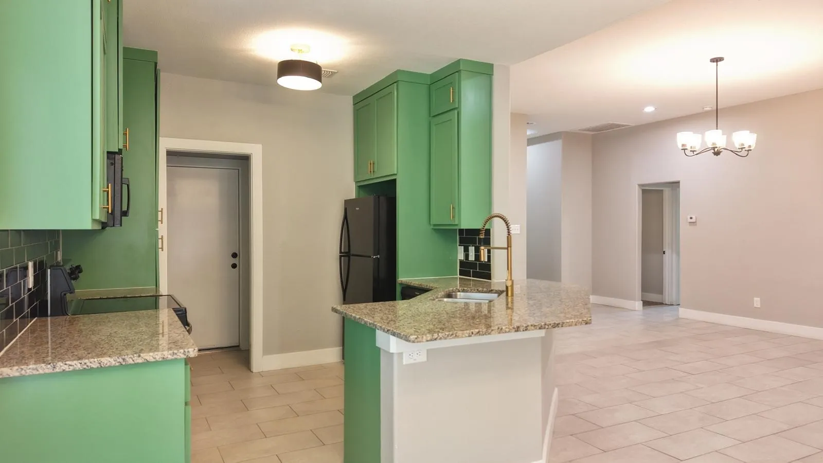 Kitchen featuring green cabinetry, granite countertops, tile backsplash, and a built-in sink with a gooseneck faucet
