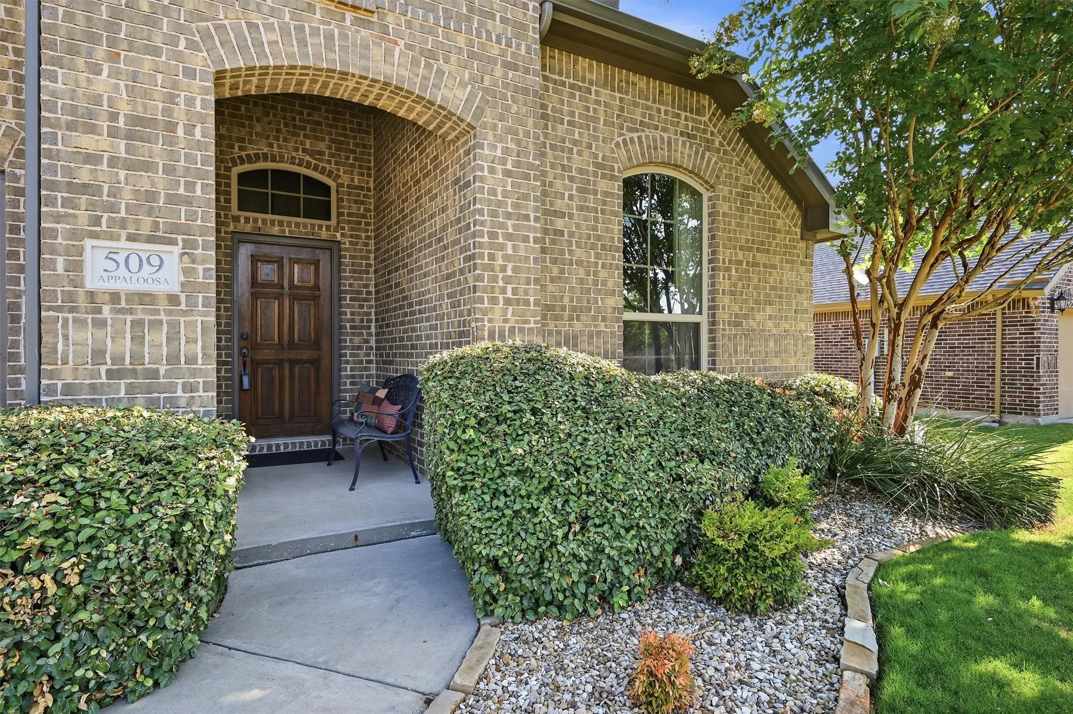 The front entry welcomes guests with a handsome wooden front door, curved archway and beautiful landscaping.