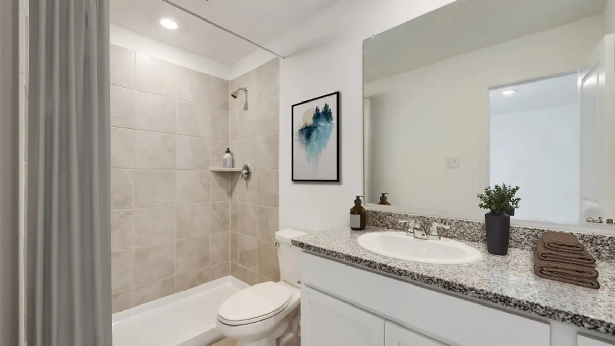 Bathroom with a tile shower, vanity, and toilet