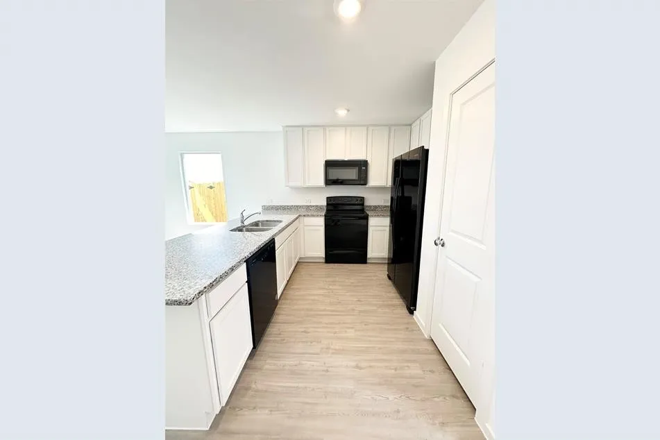 Kitchen featuring sink, white cabinets, light hardwood / wood-style flooring, black appliances, and light stone countertops