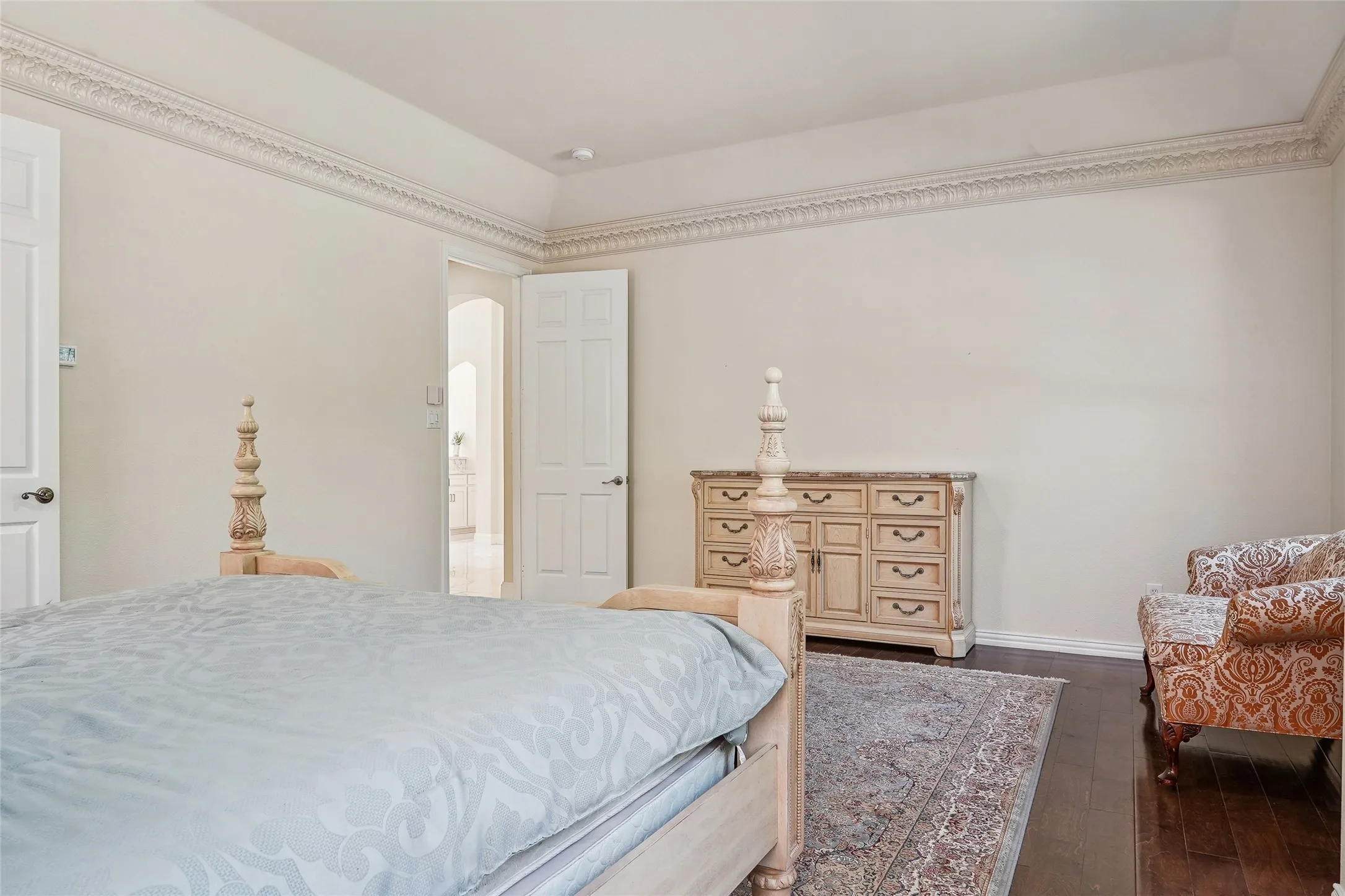 Spacious bedroom offering hardwood flooring, crown molding detail, and abundant natural light