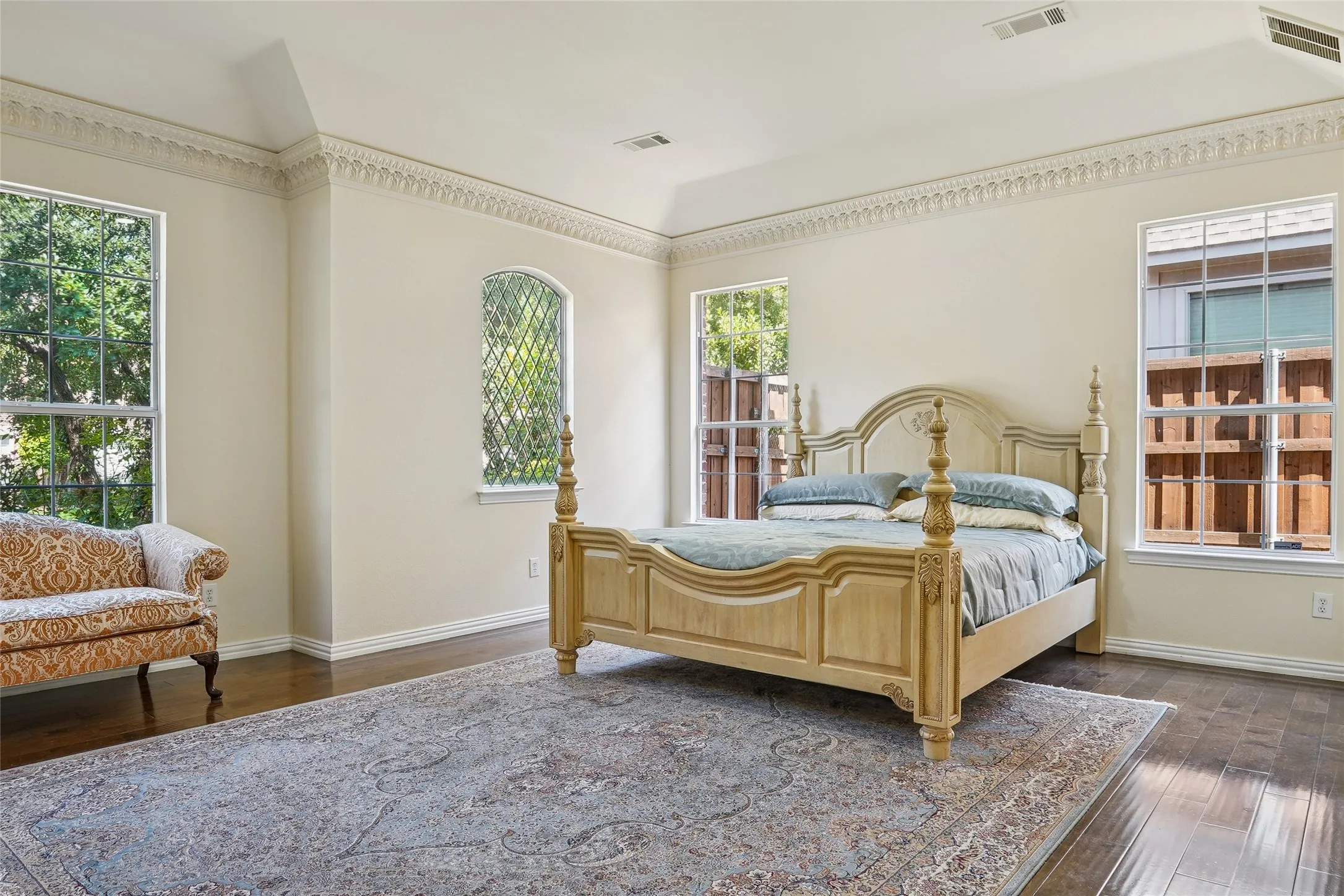 Spacious room featuring wood-finish flooring, a tray ceiling, and ornate crown molding