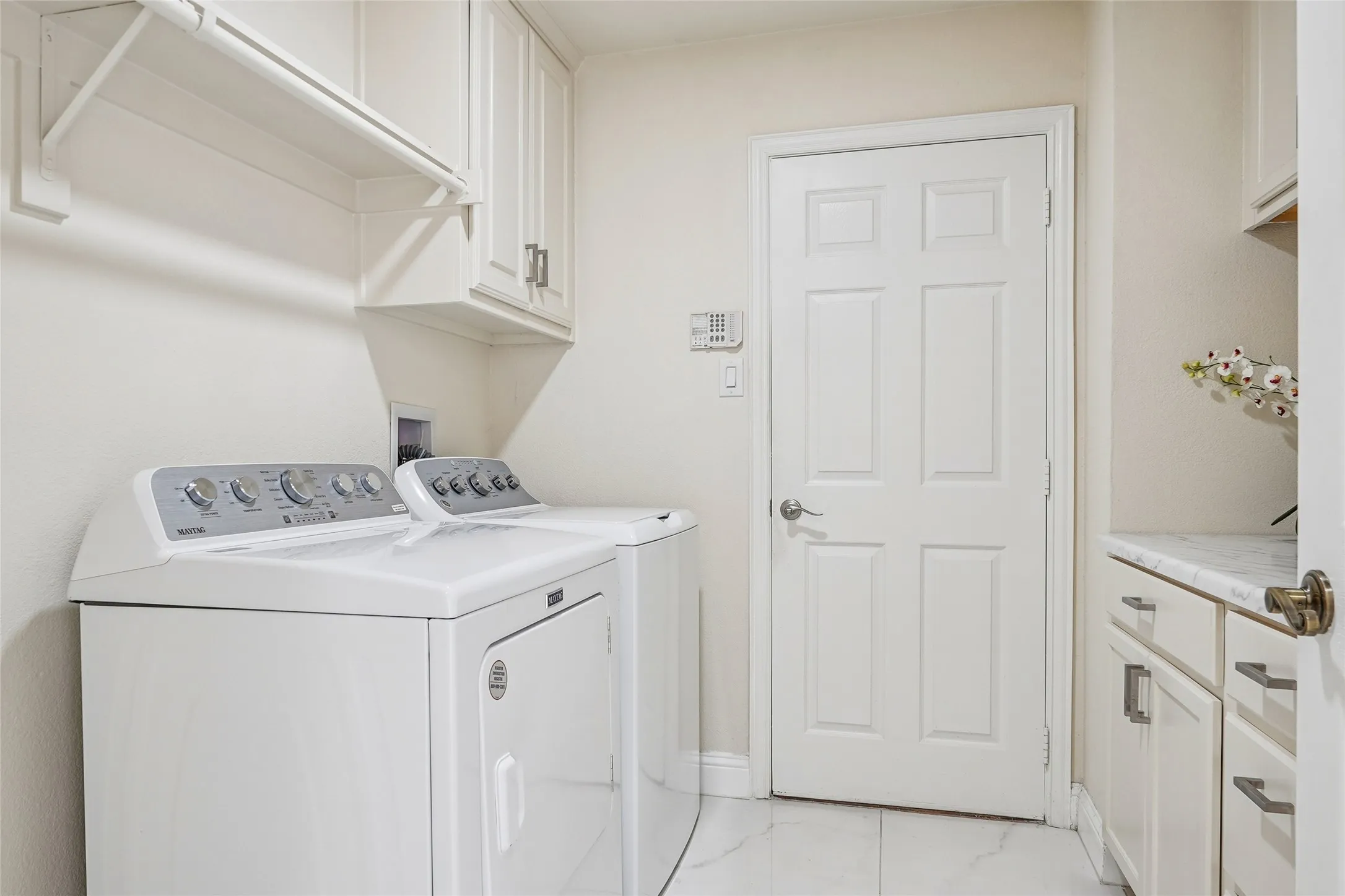 Laundry area featuring white cabinetry, a built-in hanging rod, tile flooring, and a six-panel interior door