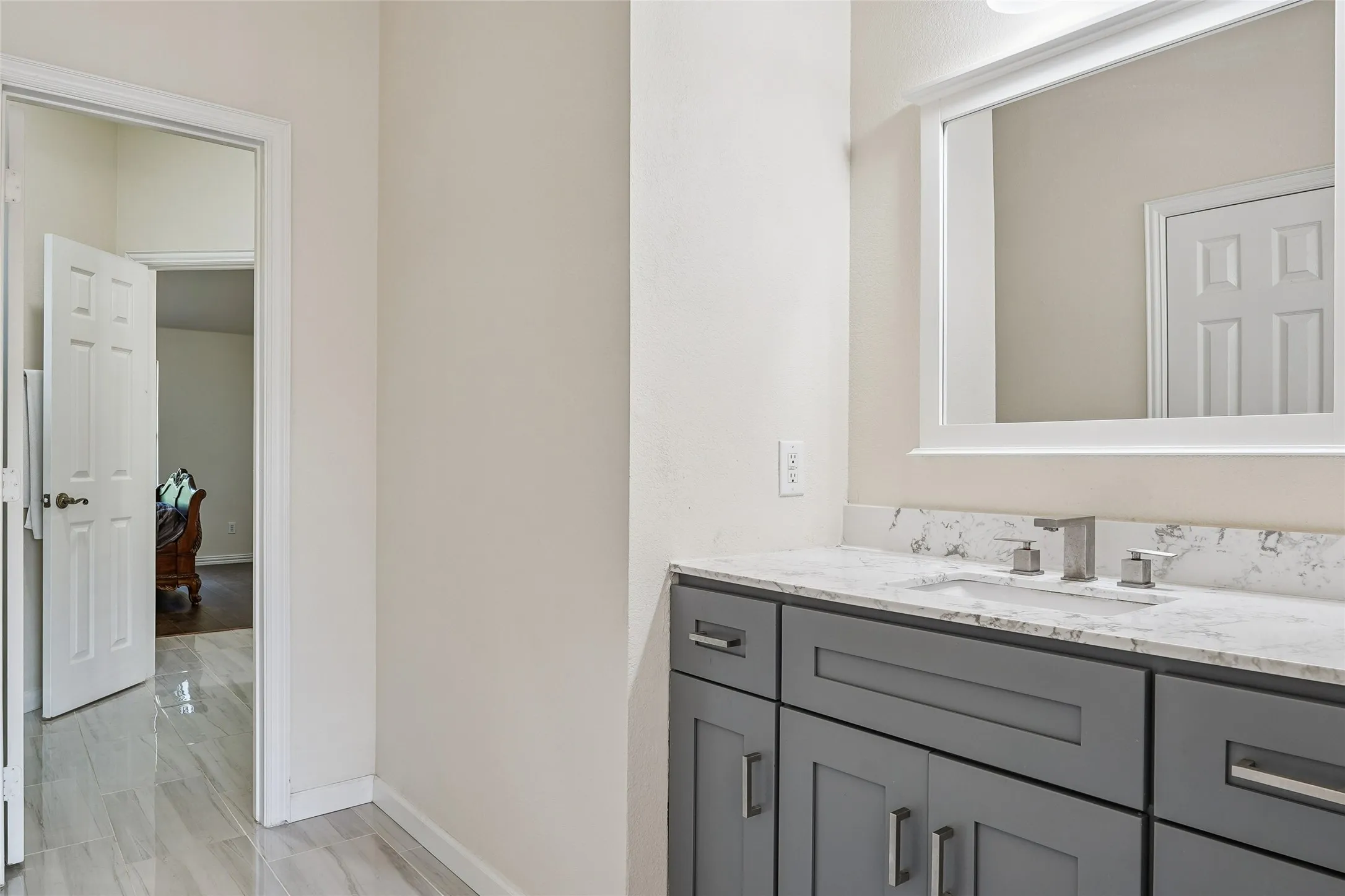 Vanity with a white countertop and integrated sink, gray shaker-style cabinetry, and a framed mirror