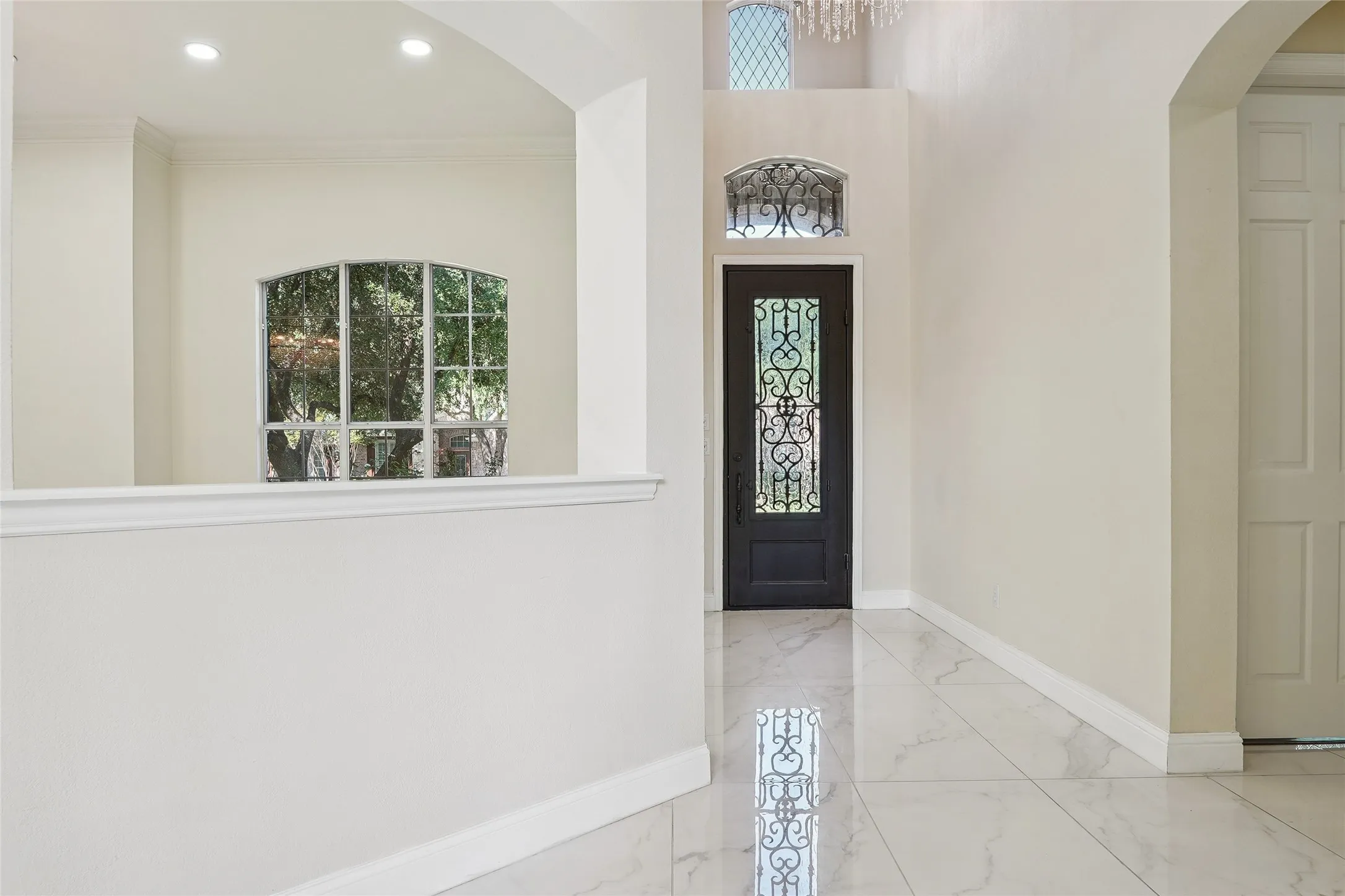 Grand foyer featuring high ceilings and a decorative wrought iron front door