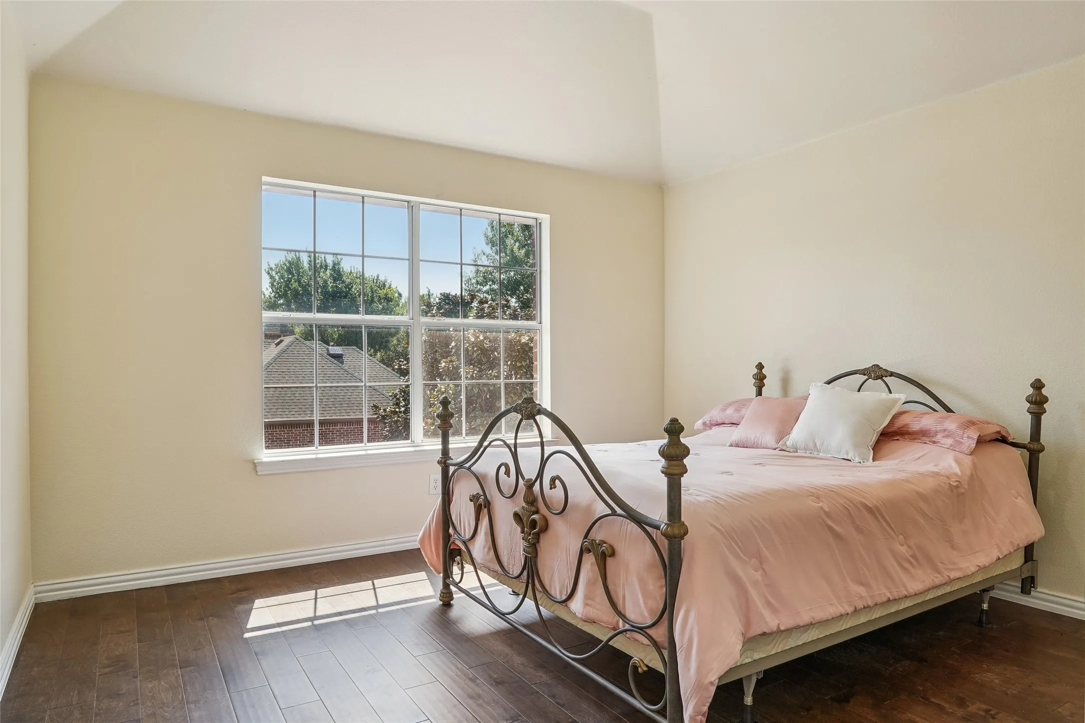Room with wood-finish flooring, light neutral walls, and a vaulted ceiling