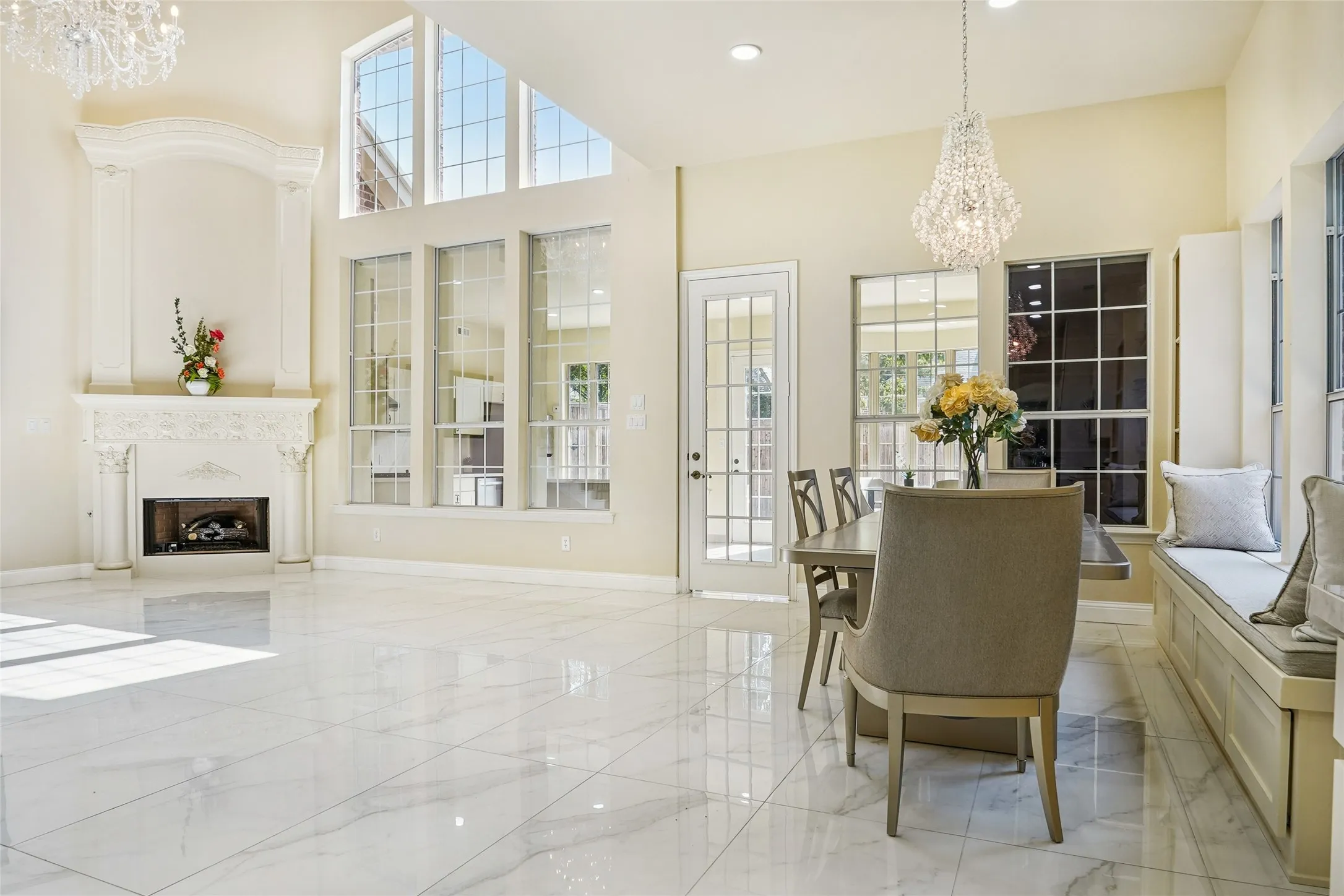 Spacious interior featuring marble-look flooring, a detailed fireplace with mantel, and tall windows