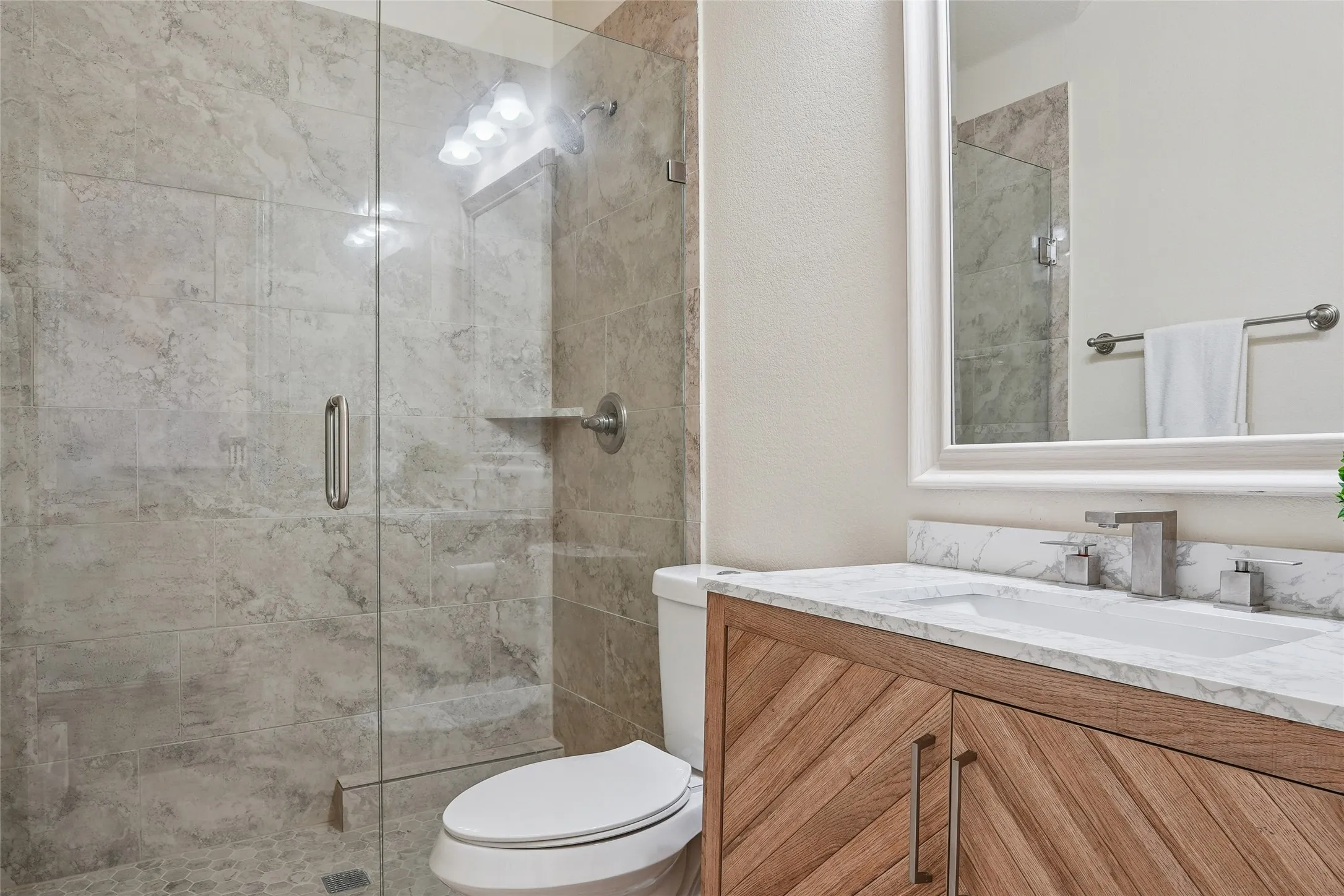 Bathroom featuring a glass-enclosed shower with pebble flooring and tiled walls