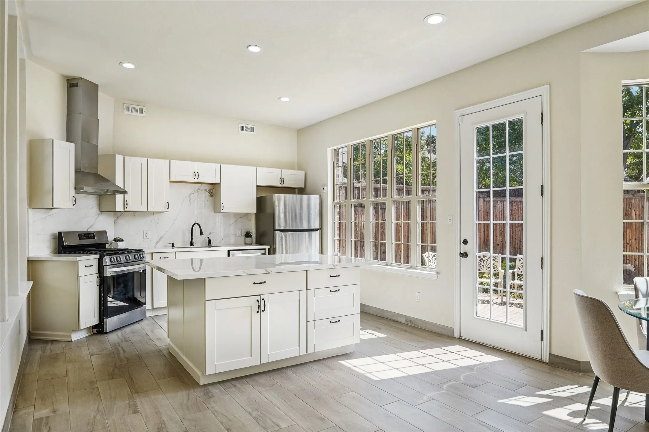 2nd kitchen featuring a central island with storage, white cabinetry, integrated stainless steel appliances, and wood-finish flooring
