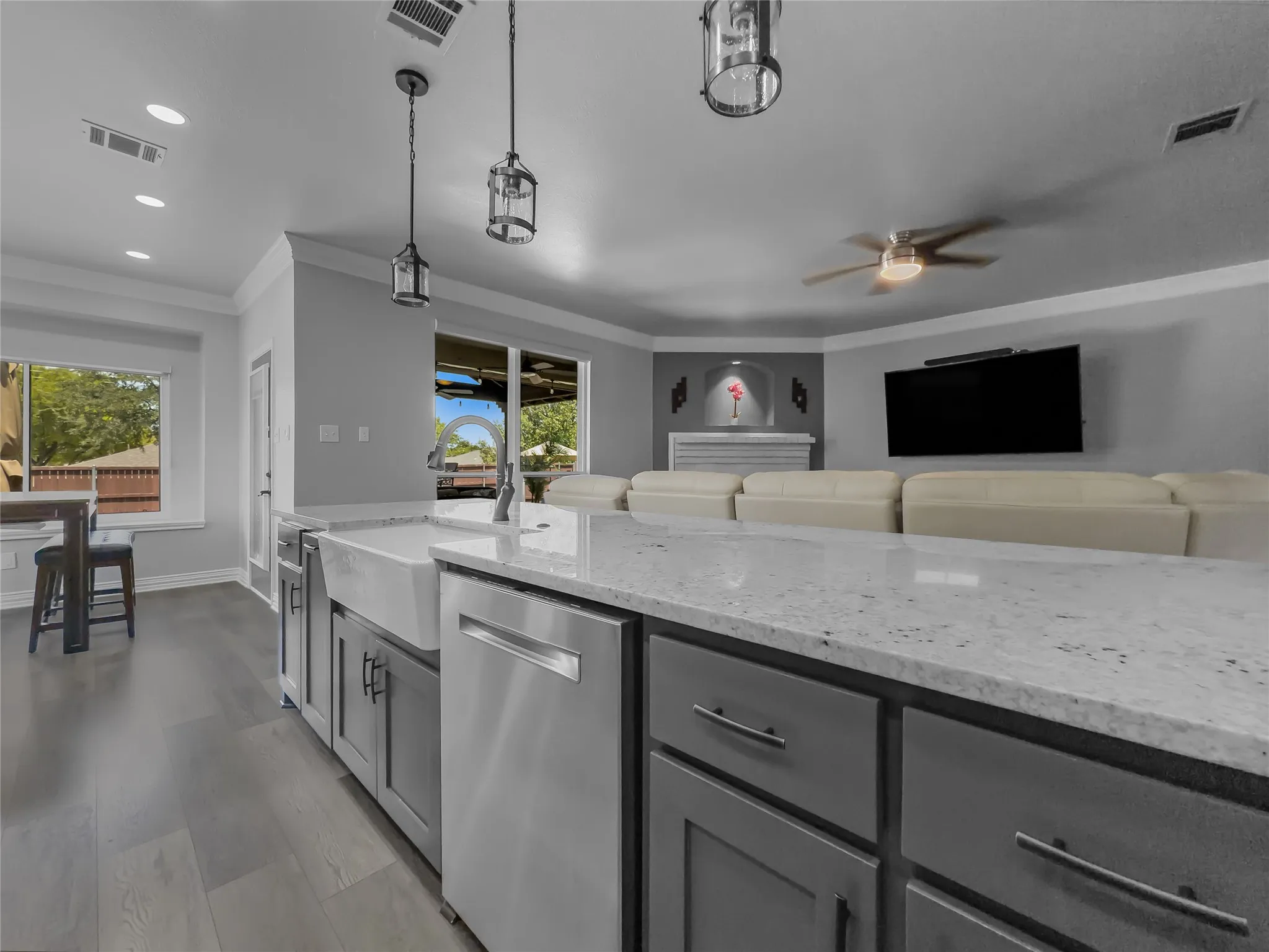 Kitchen island with a farmhouse sink, stainless steel dishwasher, and a light-toned countertop