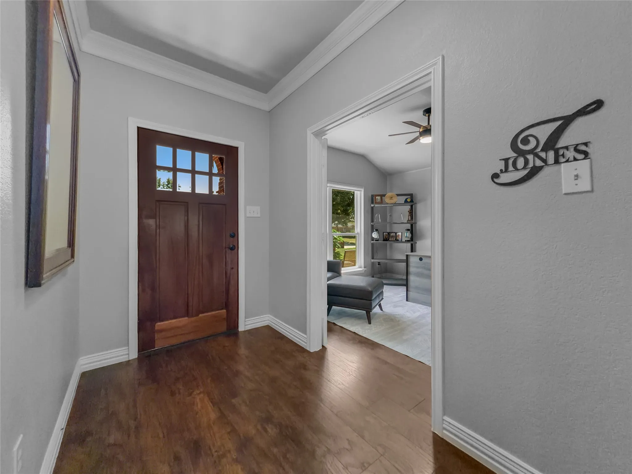 Wood-finish flooring, crown molding, and a wood entry door with divided lites