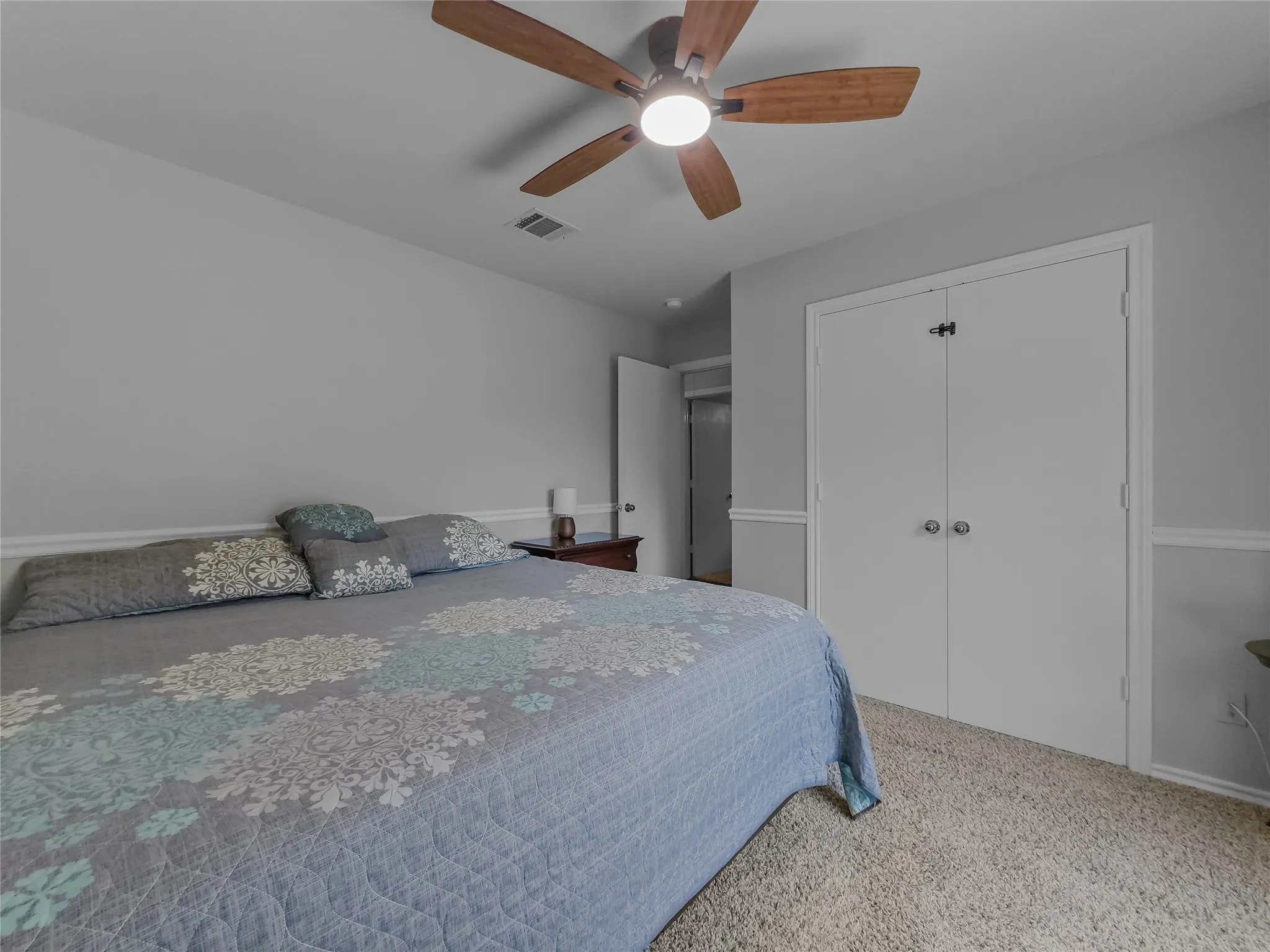 Wall-to-wall carpeting, ceiling fan with integrated lighting, paneled walls, and bi-fold closet doors