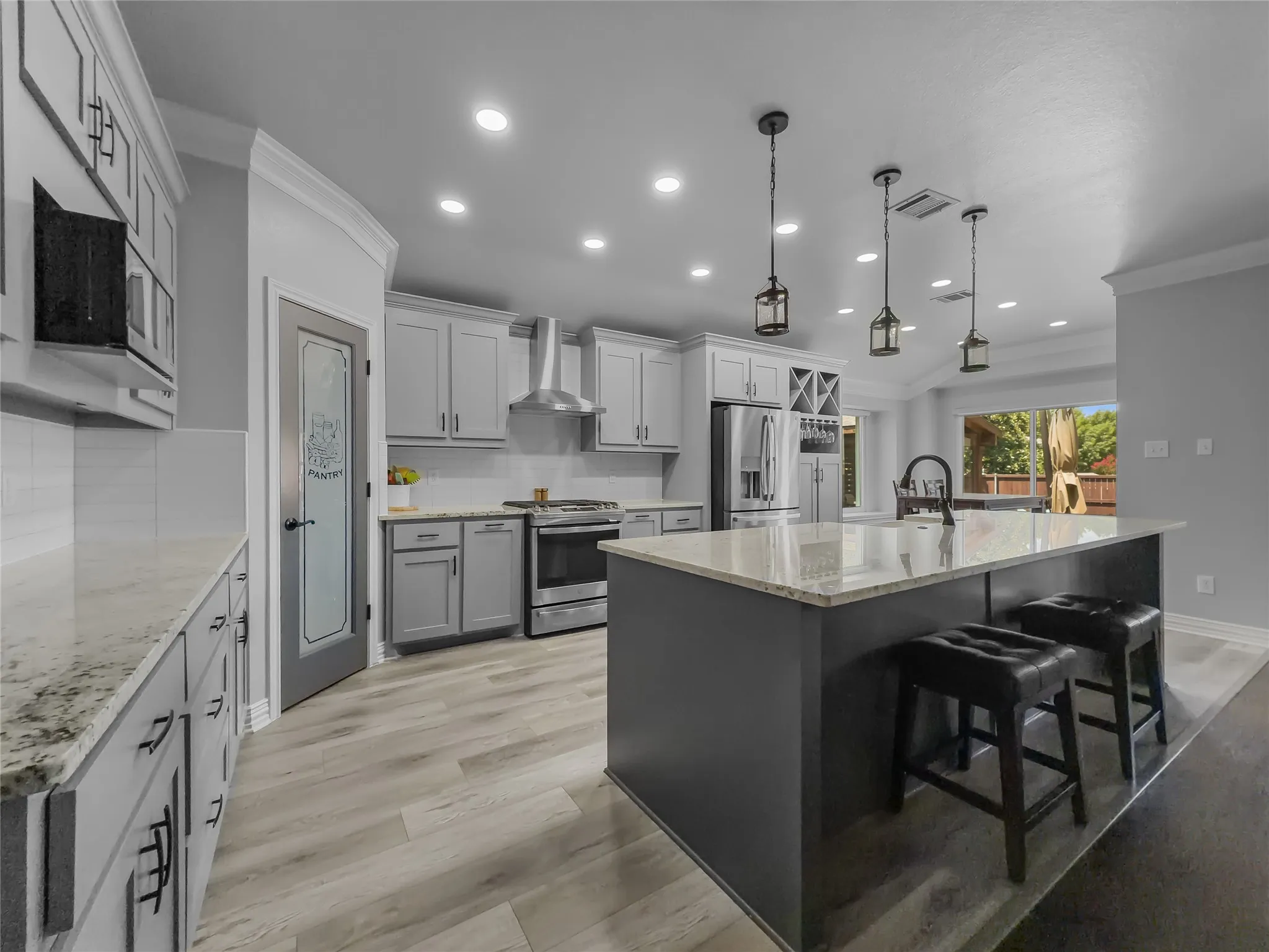Contemporary kitchen featuring light gray cabinetry, stainless steel appliances, granite countertops, and wood-finish flooring