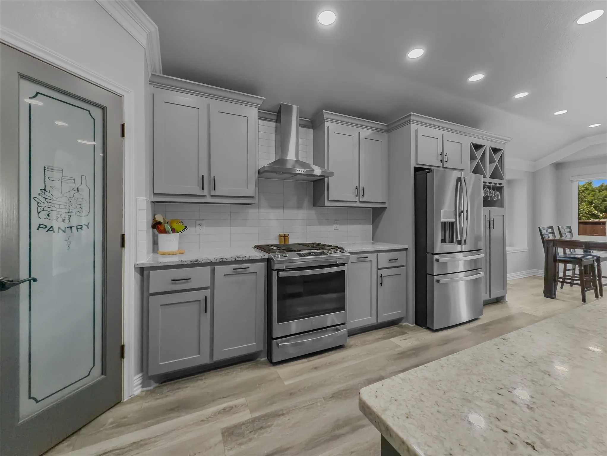 Kitchen with light gray cabinetry, stainless steel appliances, wood-finish flooring, and recessed lighting