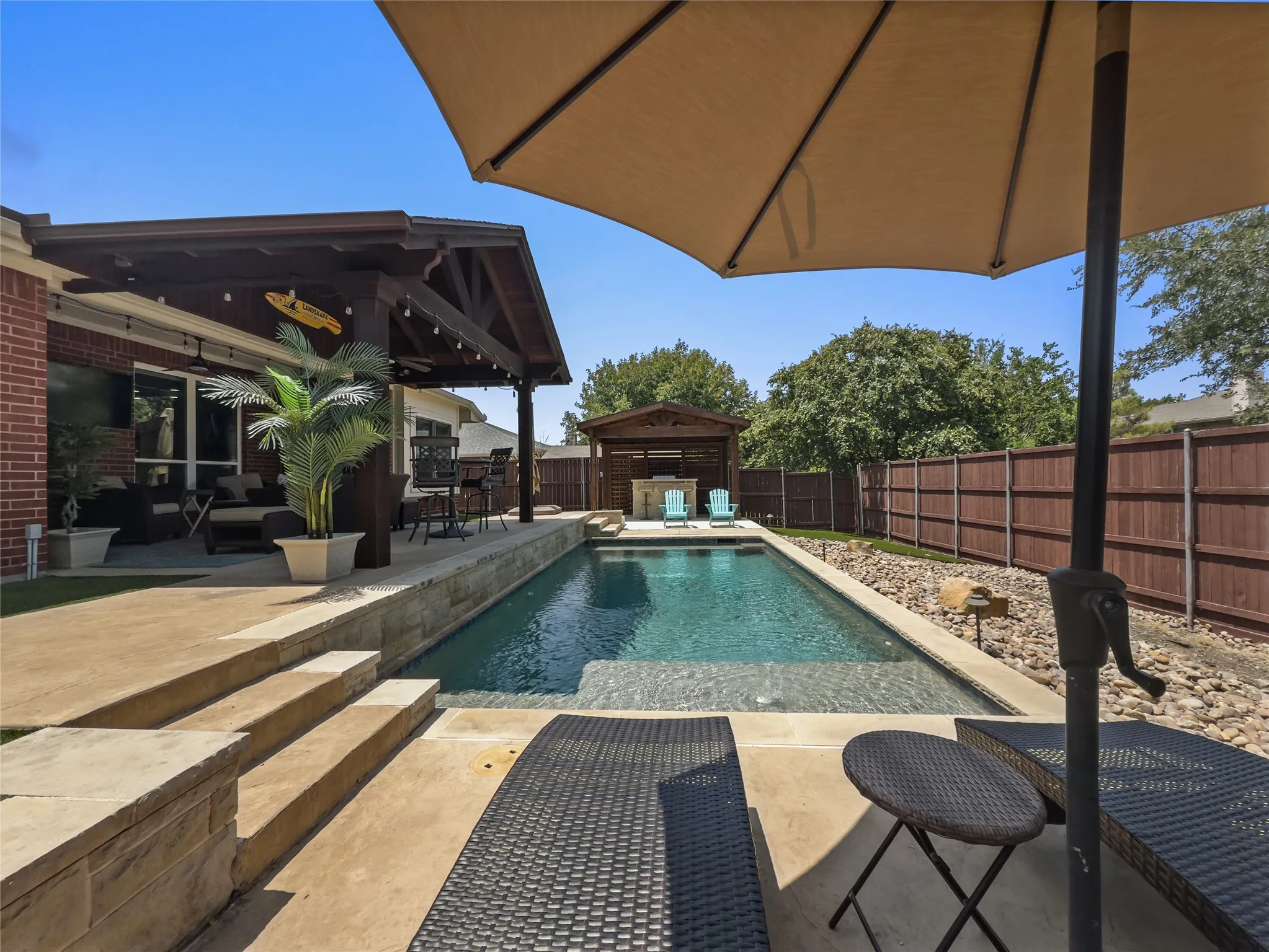 Outdoor living area featuring a covered patio, built-in swimming pool, integrated spa, and a separate outdoor structure