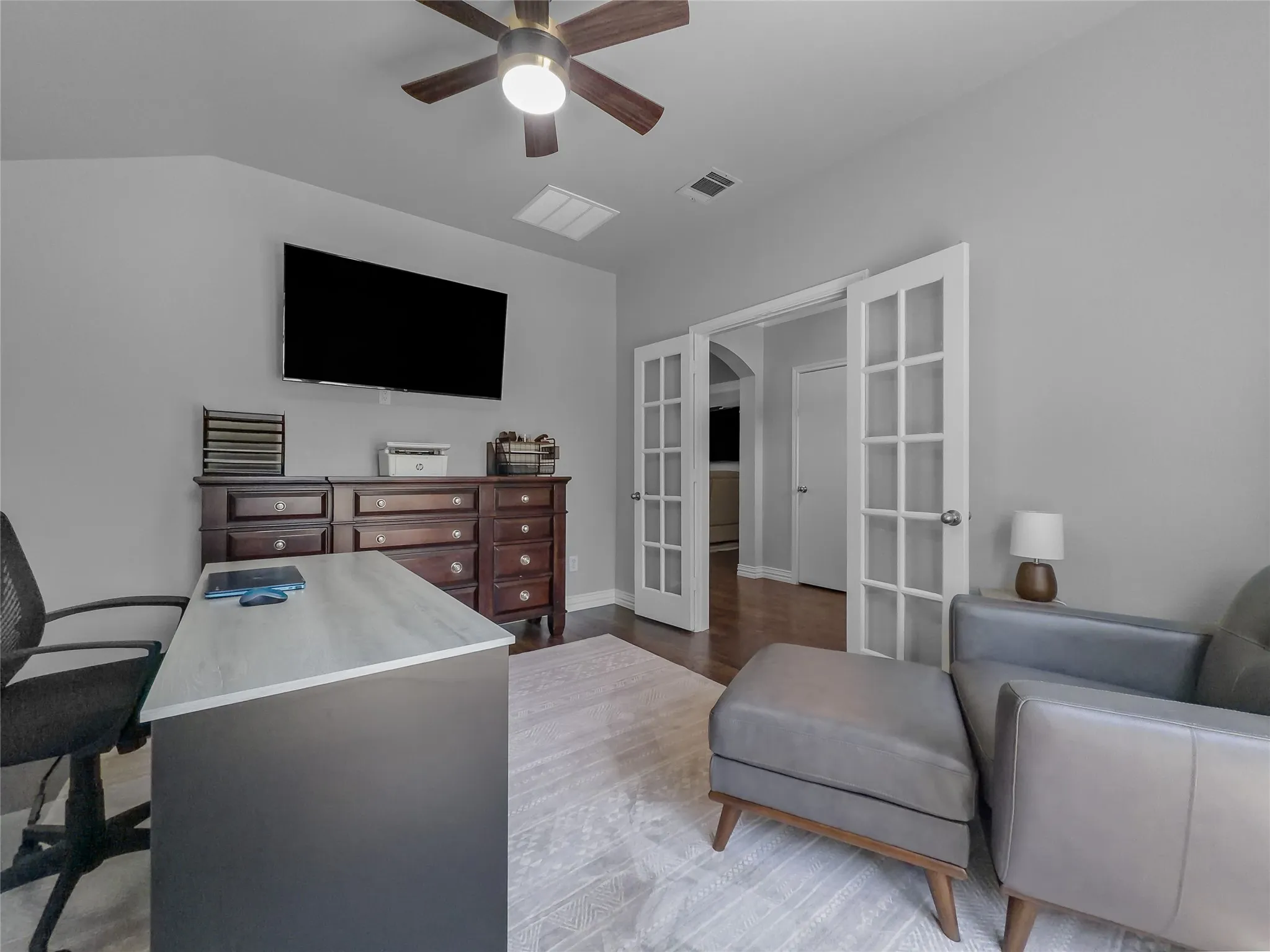 Room featuring a ceiling fan, wall-mounted television, and wood-finish flooring