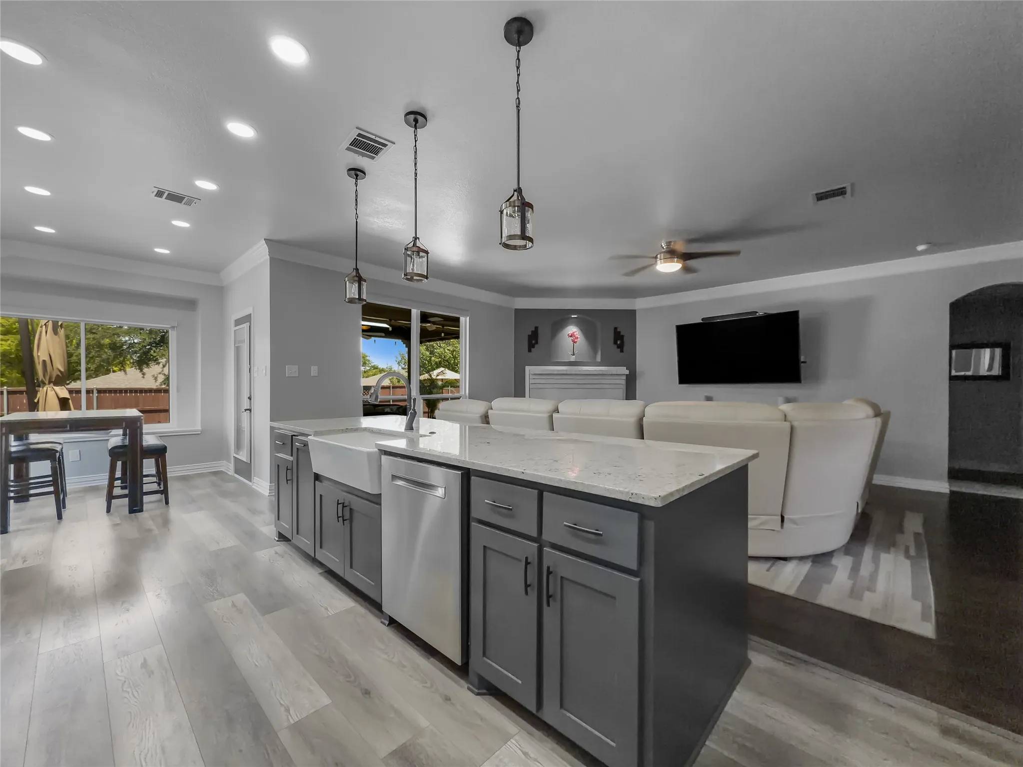 Kitchen island with a farmhouse sink, stainless steel dishwasher, and pendant lighting