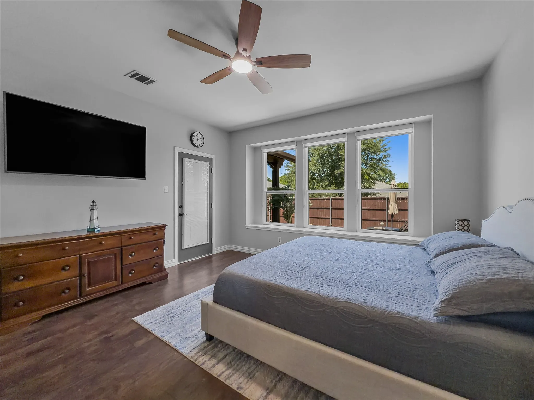 Wood-finish flooring, ceiling fan, multiple windows, and a glass-paneled door