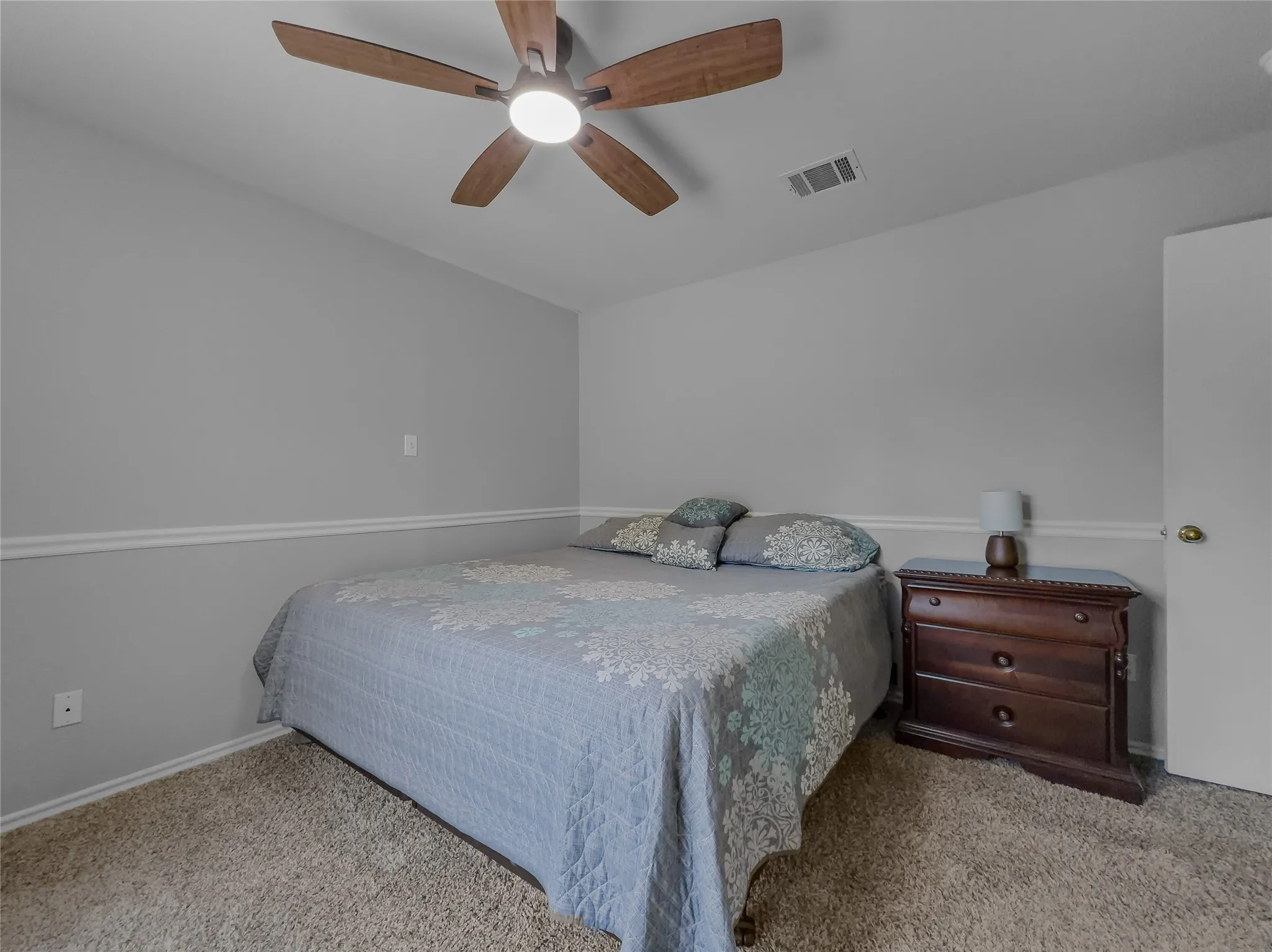 Carpeted flooring, crown molding, ceiling fan with integrated lighting, and a paneled door with a brass-finish knob