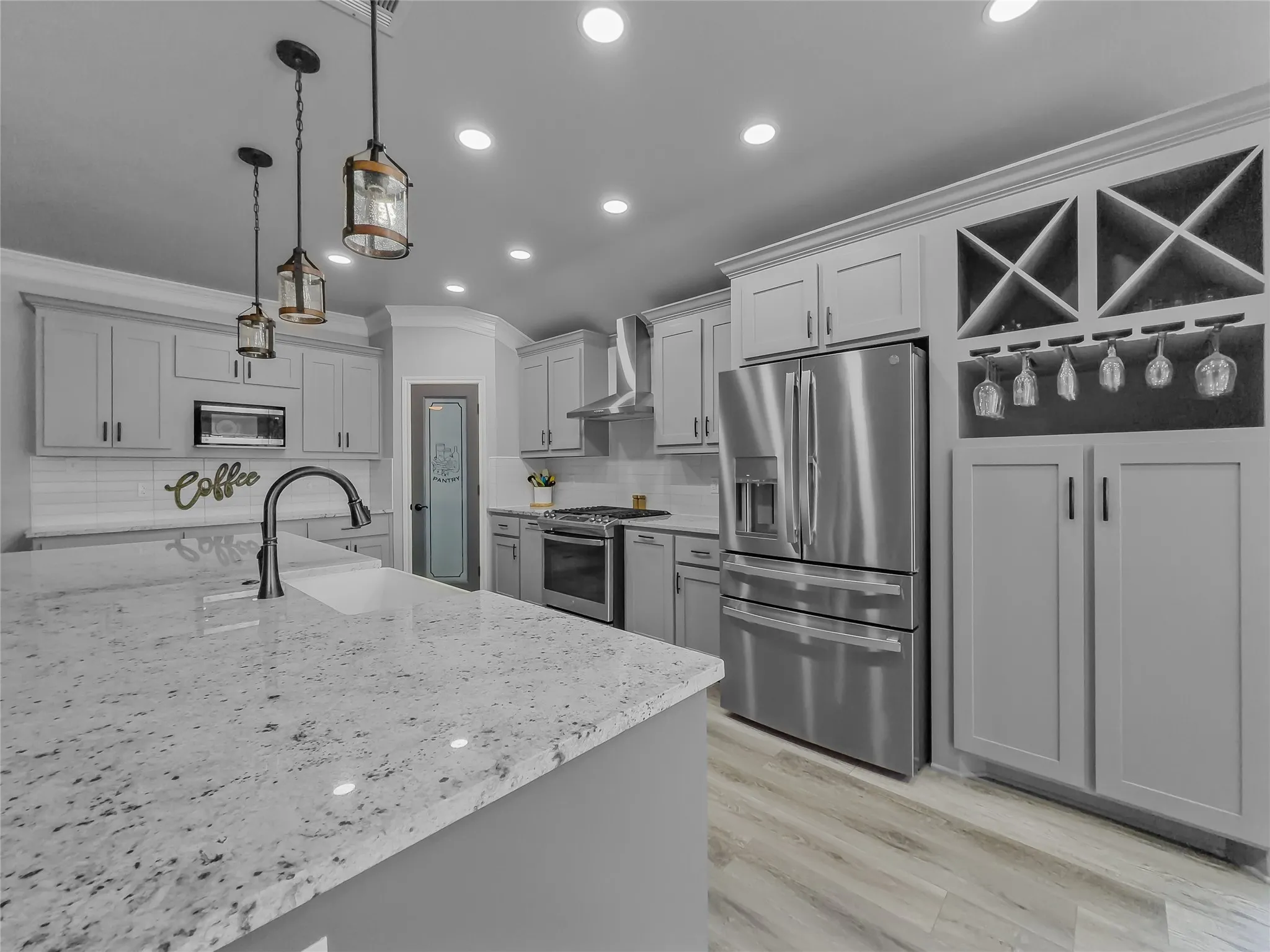 Kitchen featuring light gray cabinetry, stainless steel appliances, speckled stone countertops, wood-finish flooring, and a built-in wine rack